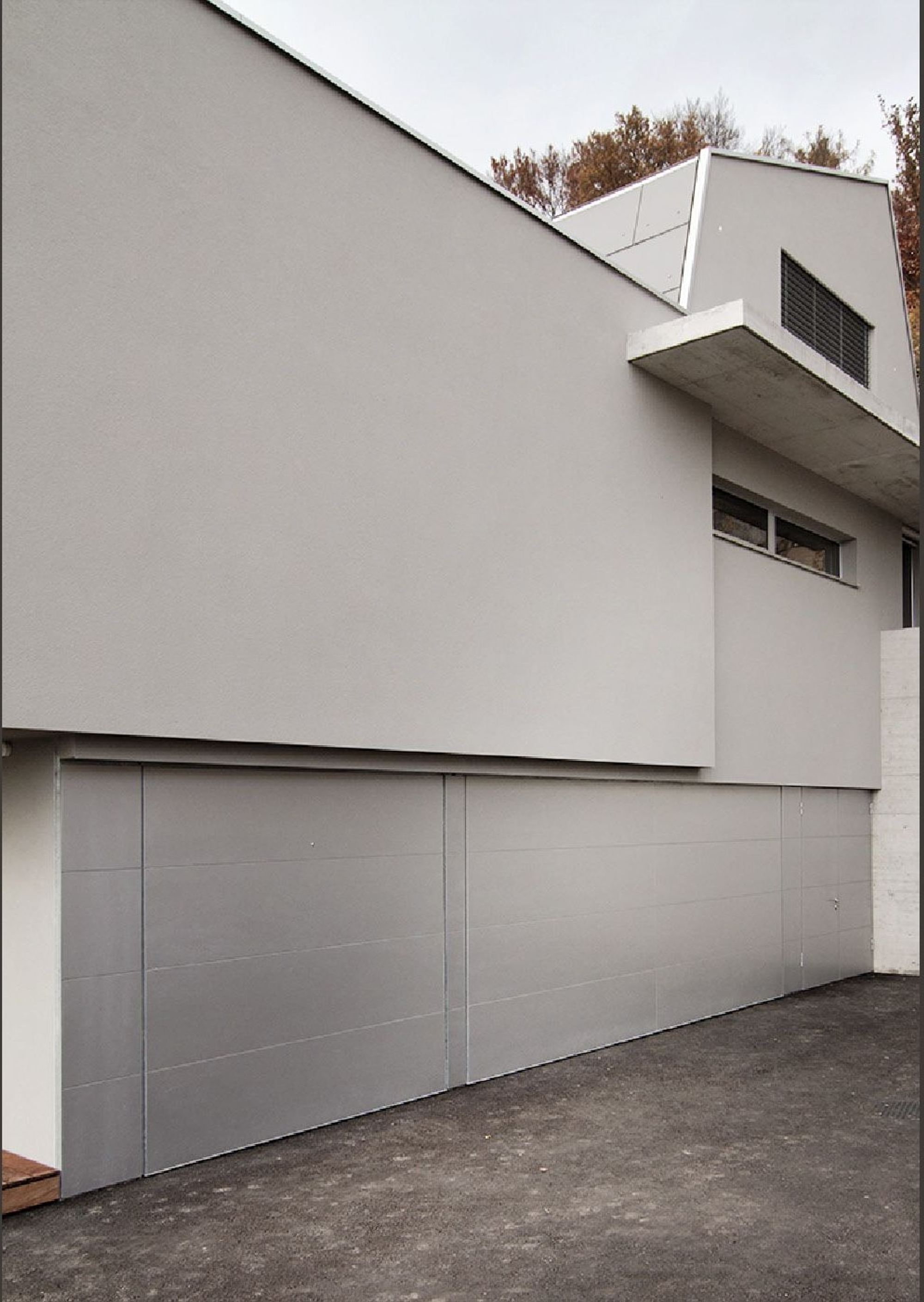 Garage with grey door and upper volume – Single-family house in Boppelsen
