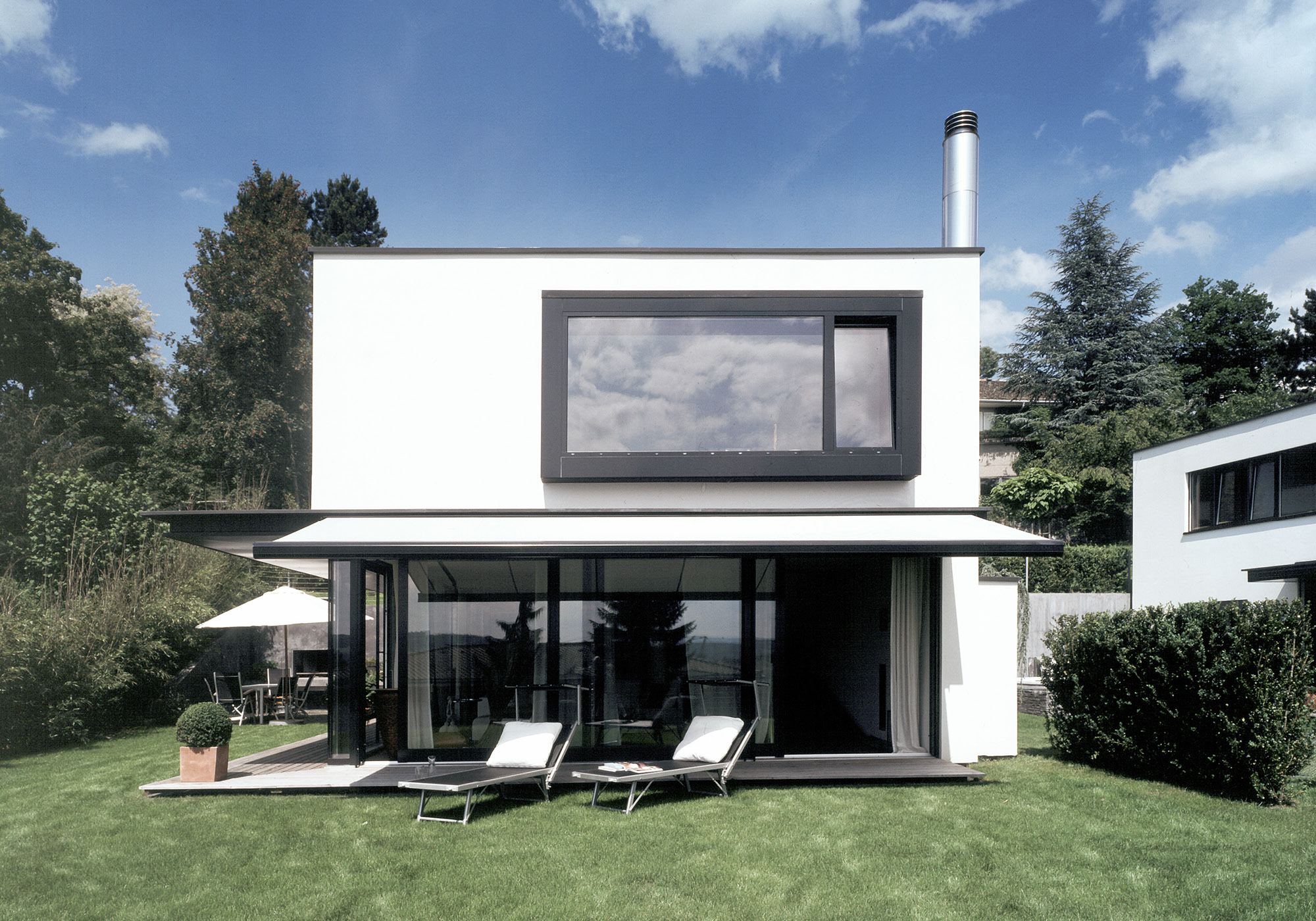 White house with framed window and loungers in the garden – Single-family house in Uitikon