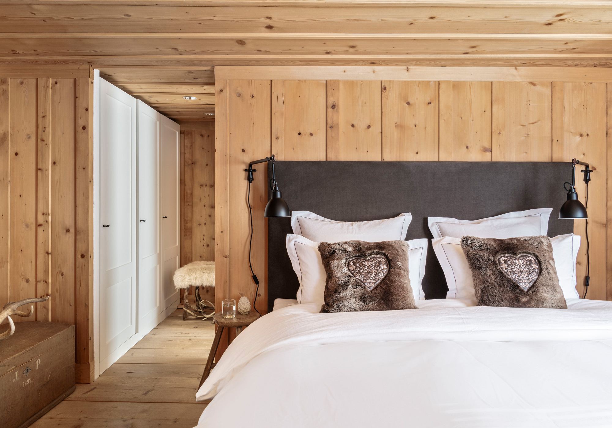 Bedroom with reclaimed timber wall and built-in wardrobe – Historic conversion in Fidaz
