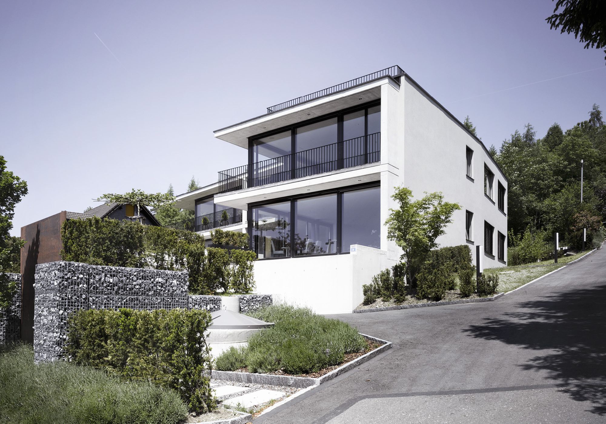 Corner of the house with gabion wall by the street – Apartment building in Uitikon