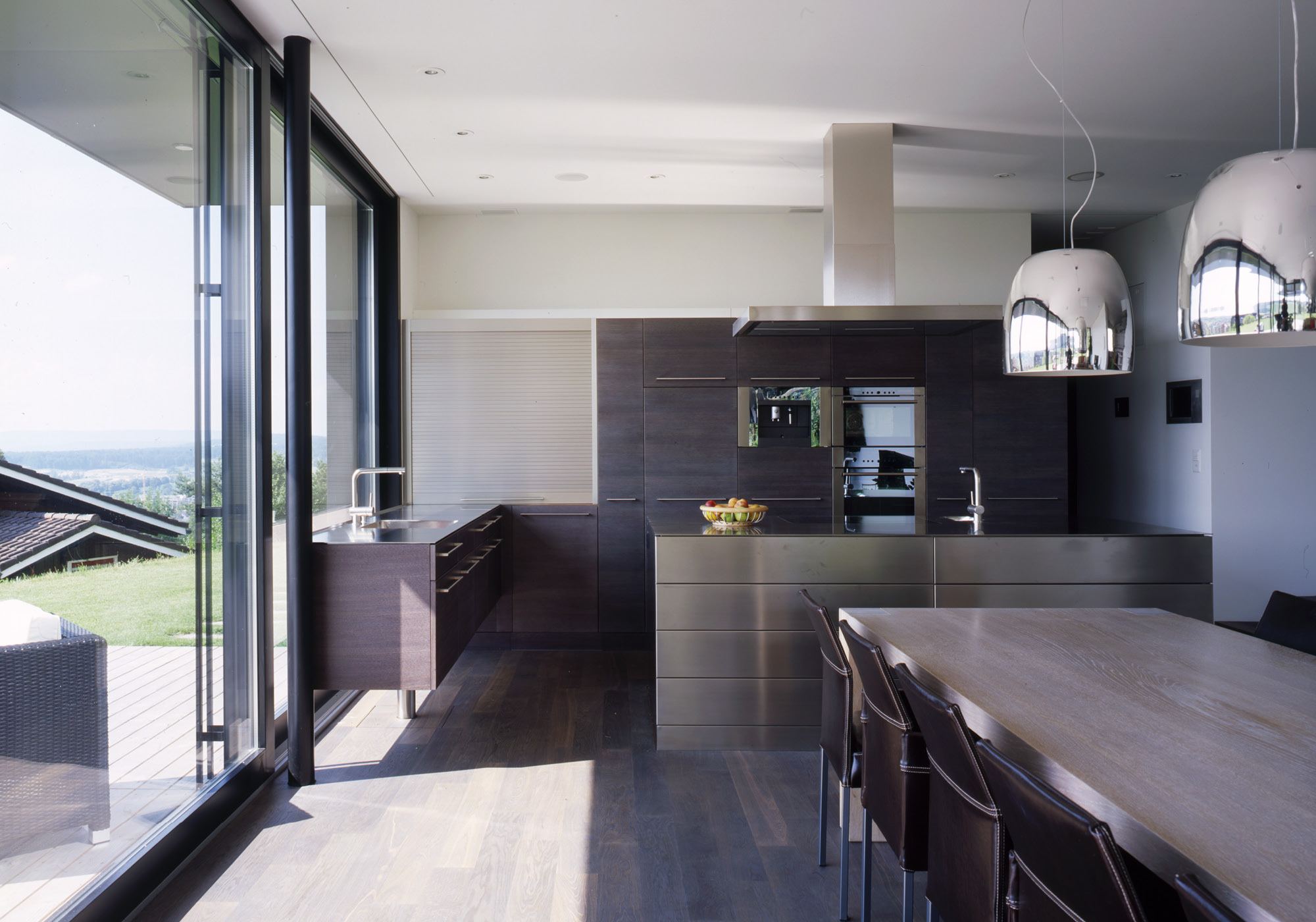 Kitchen with chrome pendant lights and dark floor – Single-family house in Bonstetten