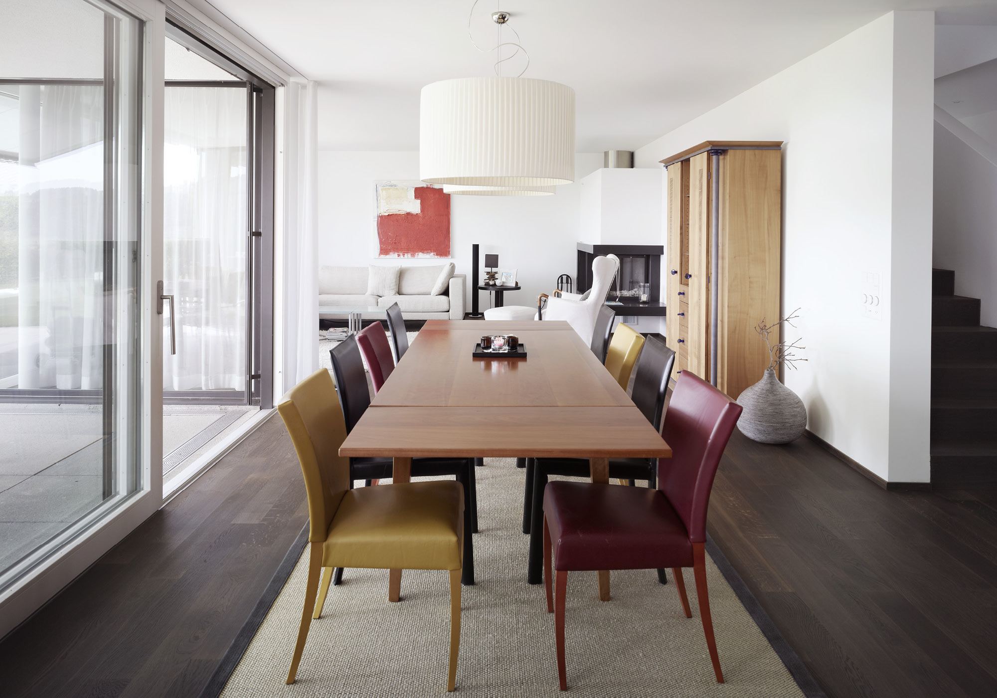 Long dining table with coloured chairs – Single-family house in Russikon