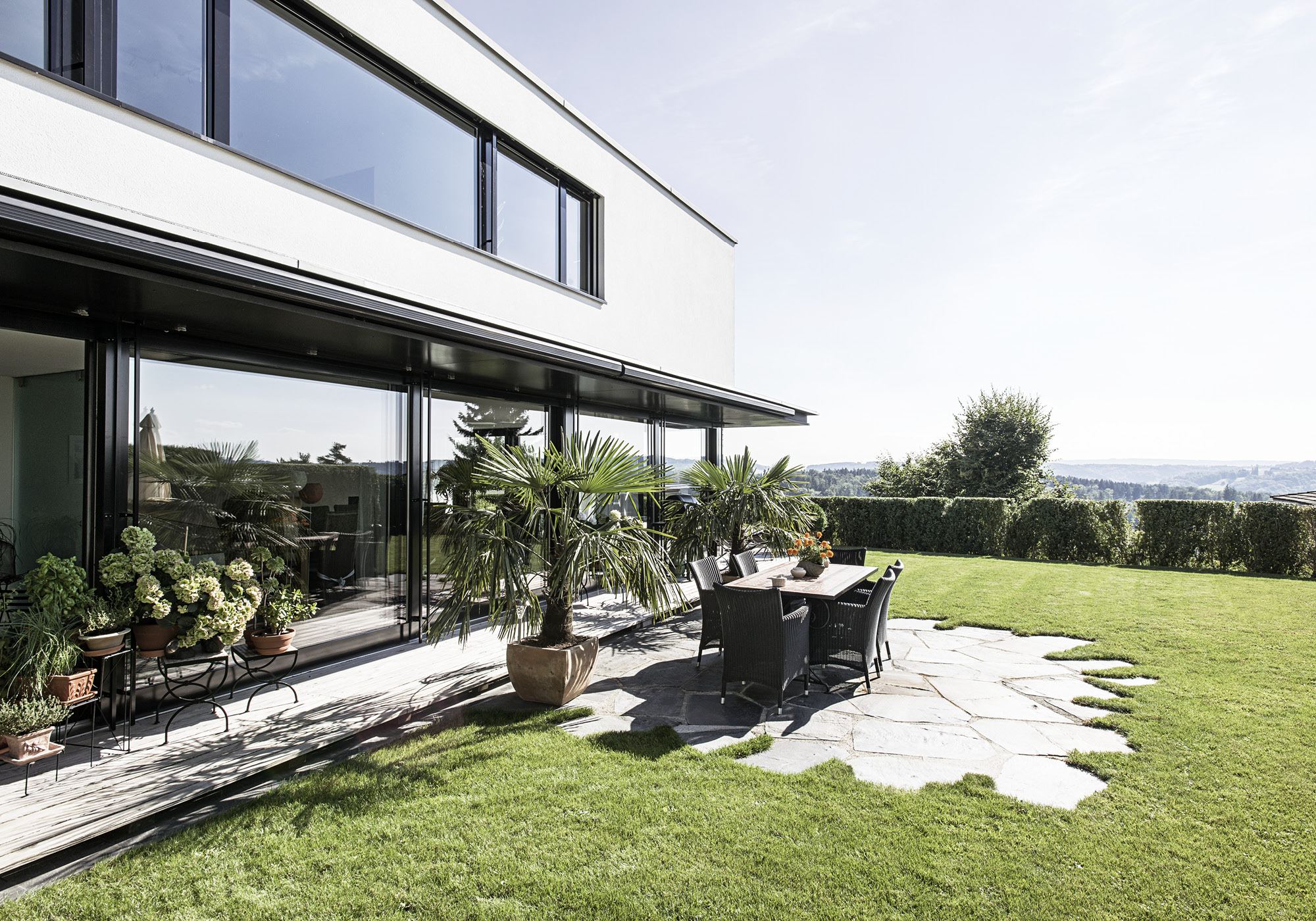 Terrace with natural stone slabs and palms – Single-family house in Uitikon