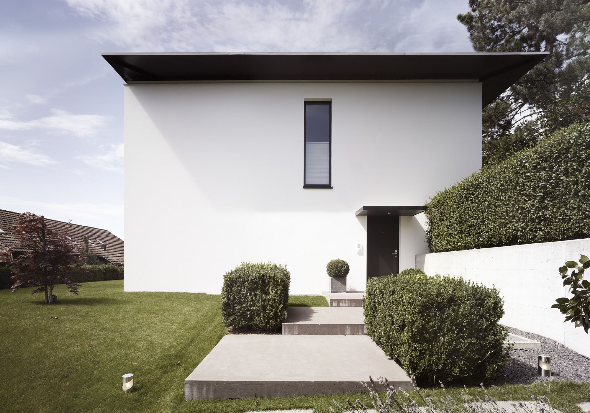 White facade with paved path and box balls – Interiors and landscape, Uitikon