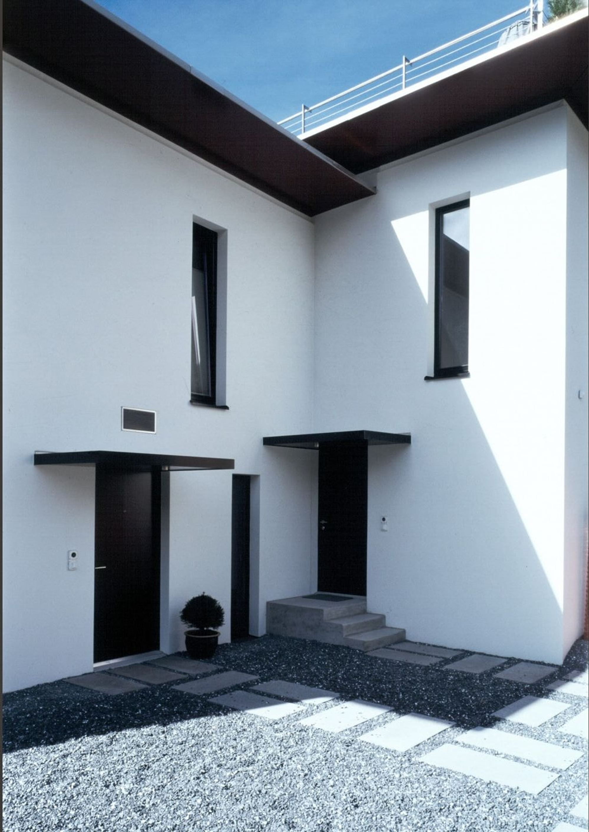 Entrance with gravel forecourt and white facade – Single-family house in Davos Platz