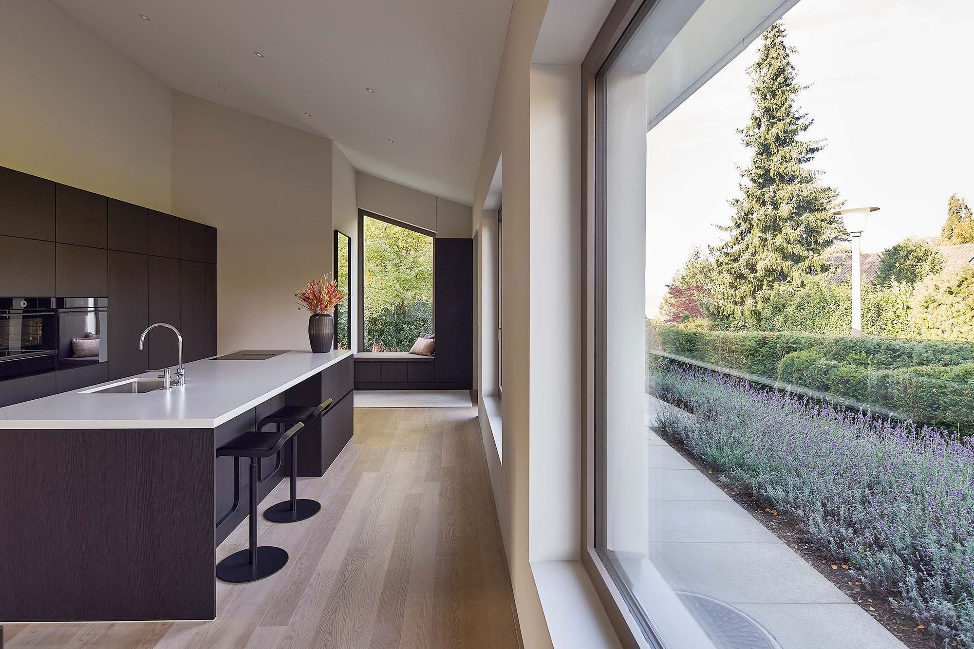 Kitchen run with bar stools and large window – Interiors and landscape, Zumikon