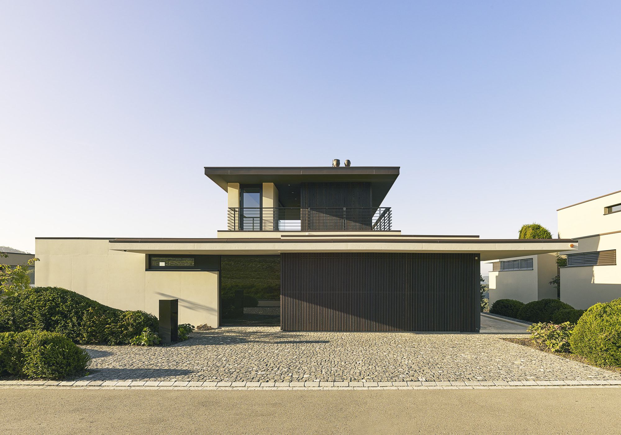 Entrance side with gravel forecourt and timber facade – Single-family house in Uitikon