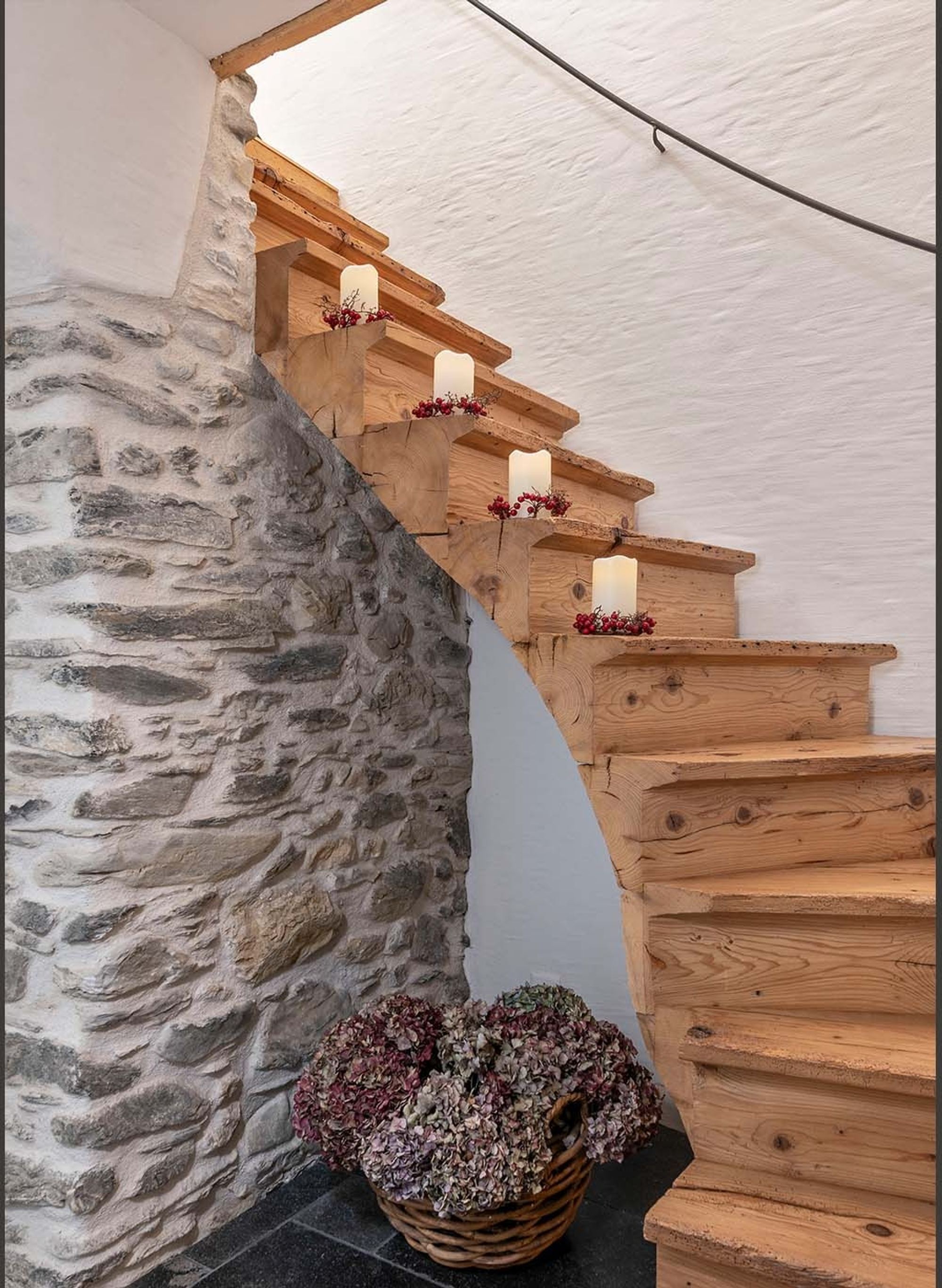 Timber staircase along a natural stone wall – Historic conversion in Fidaz