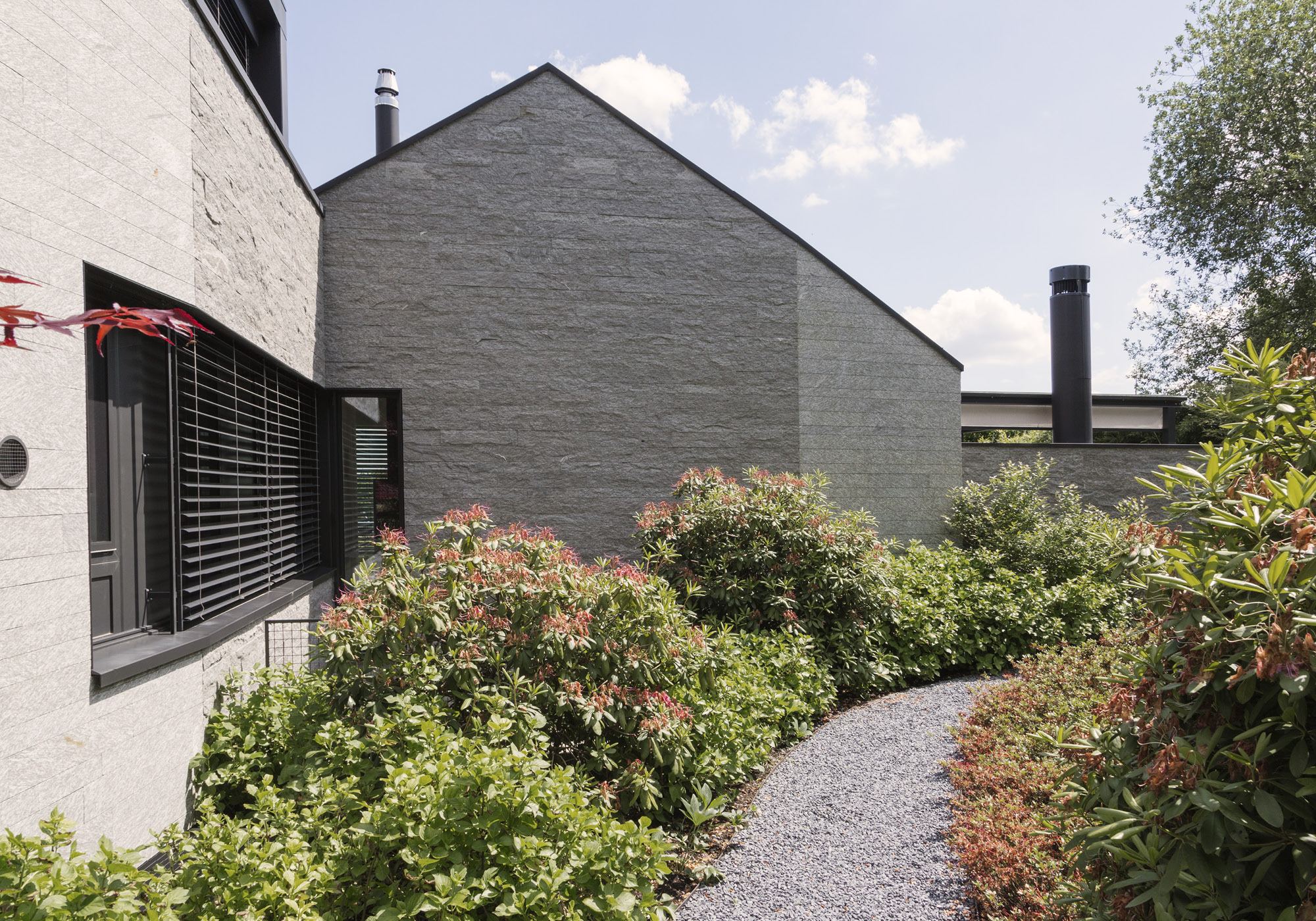 Side facade with stone cladding and garden – Single-family house in Neerach
