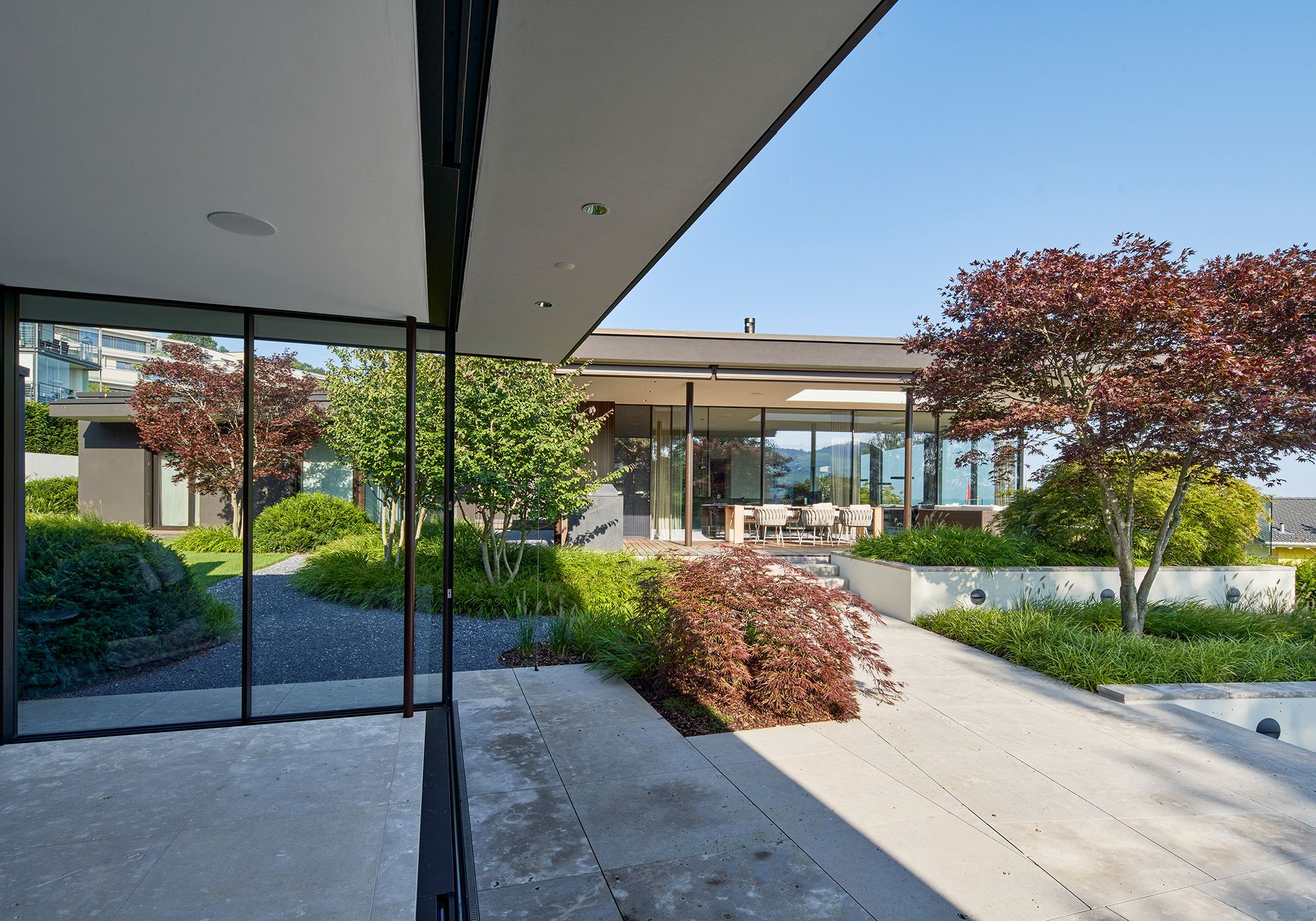 View from the frameless glass corner into the planted courtyard – Single-family house in Schindellegi