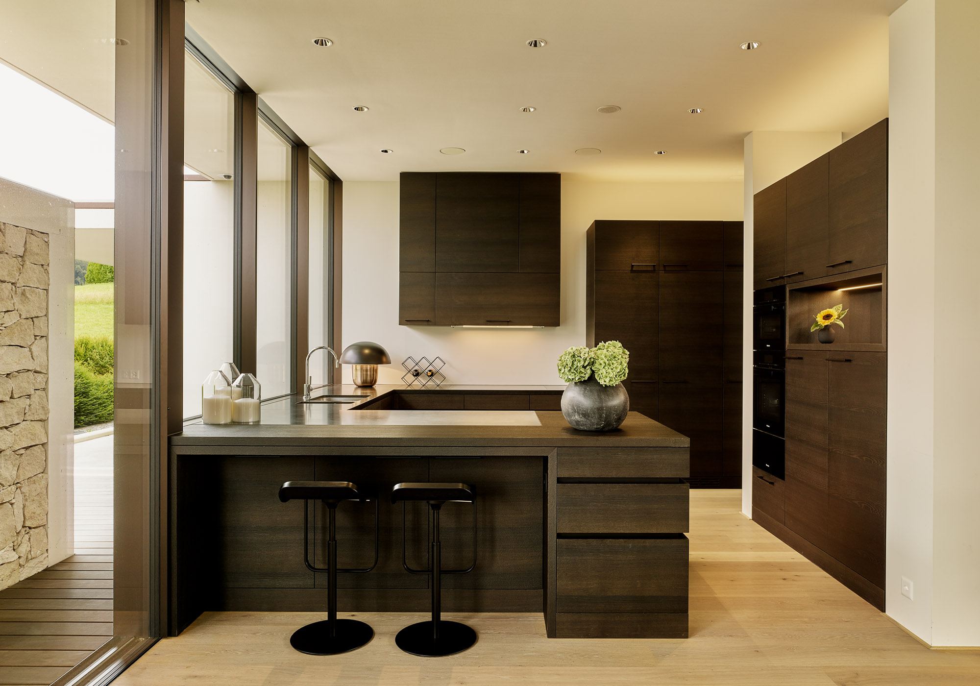 Kitchen with dark timber fronts and bar stools – Single-family house in Uitikon