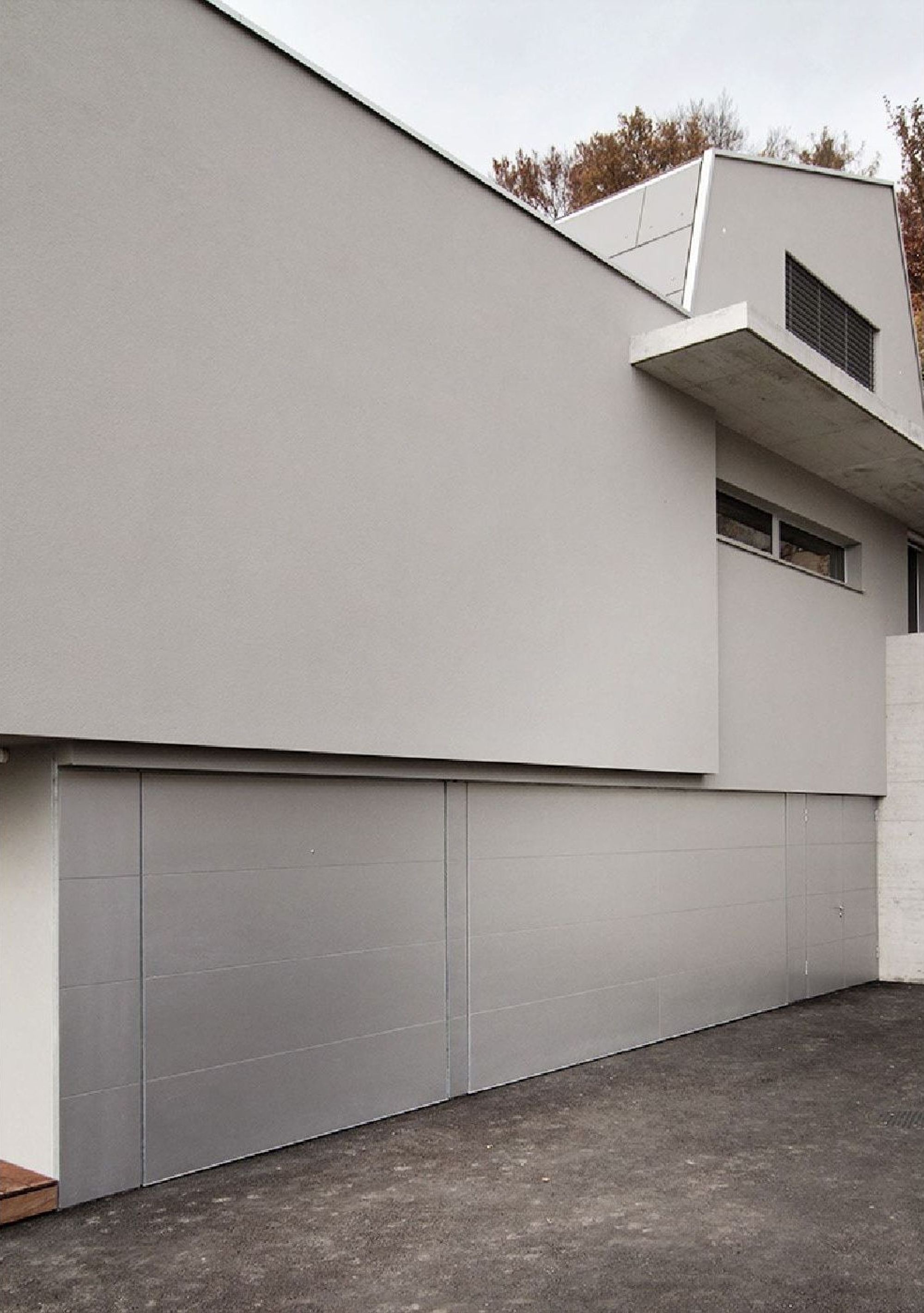 Garage with grey door and upper volume – Single-family house in Boppelsen