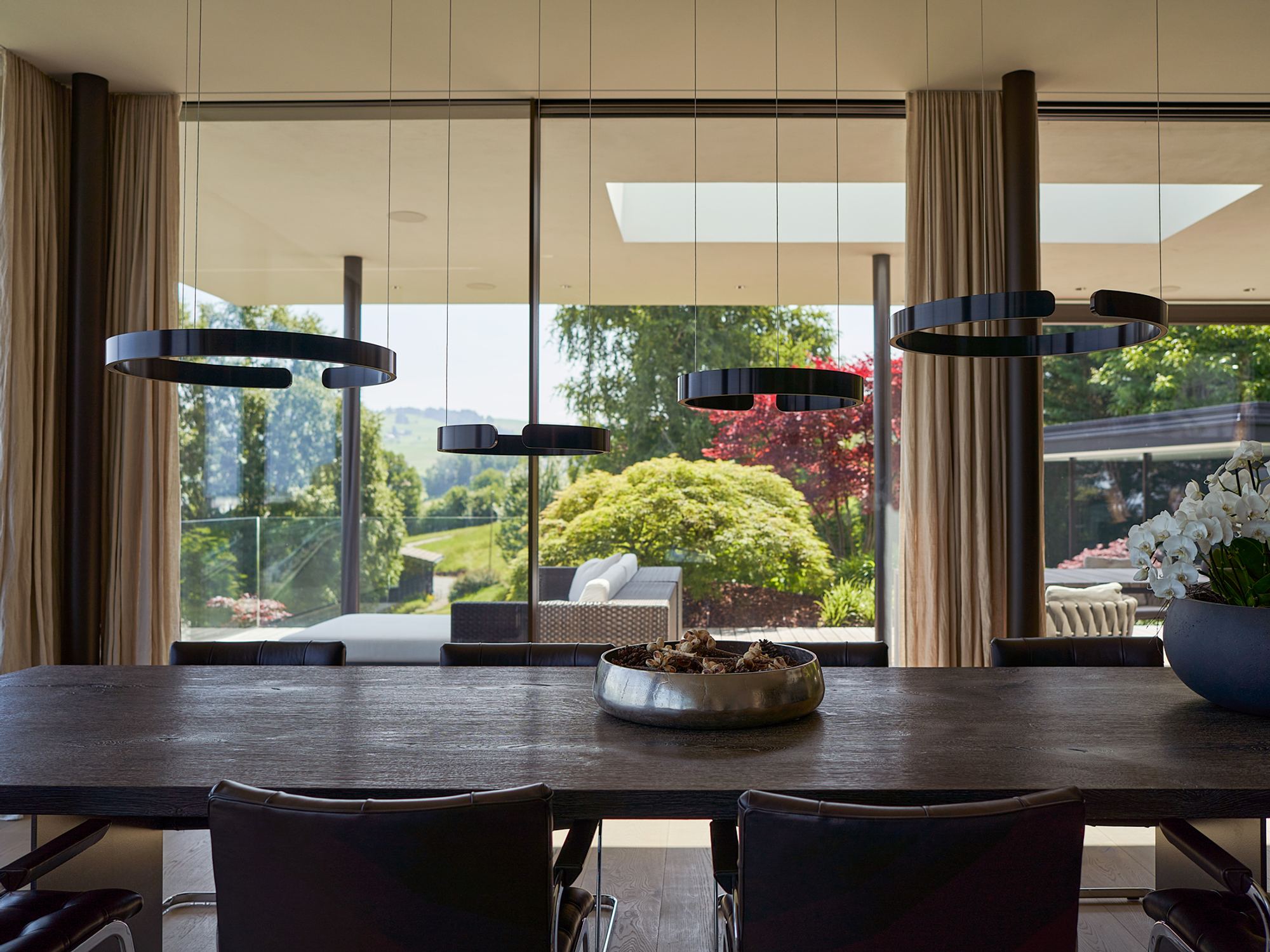 Dining area with ring pendants and view into the garden – Single-family house in Schindellegi
