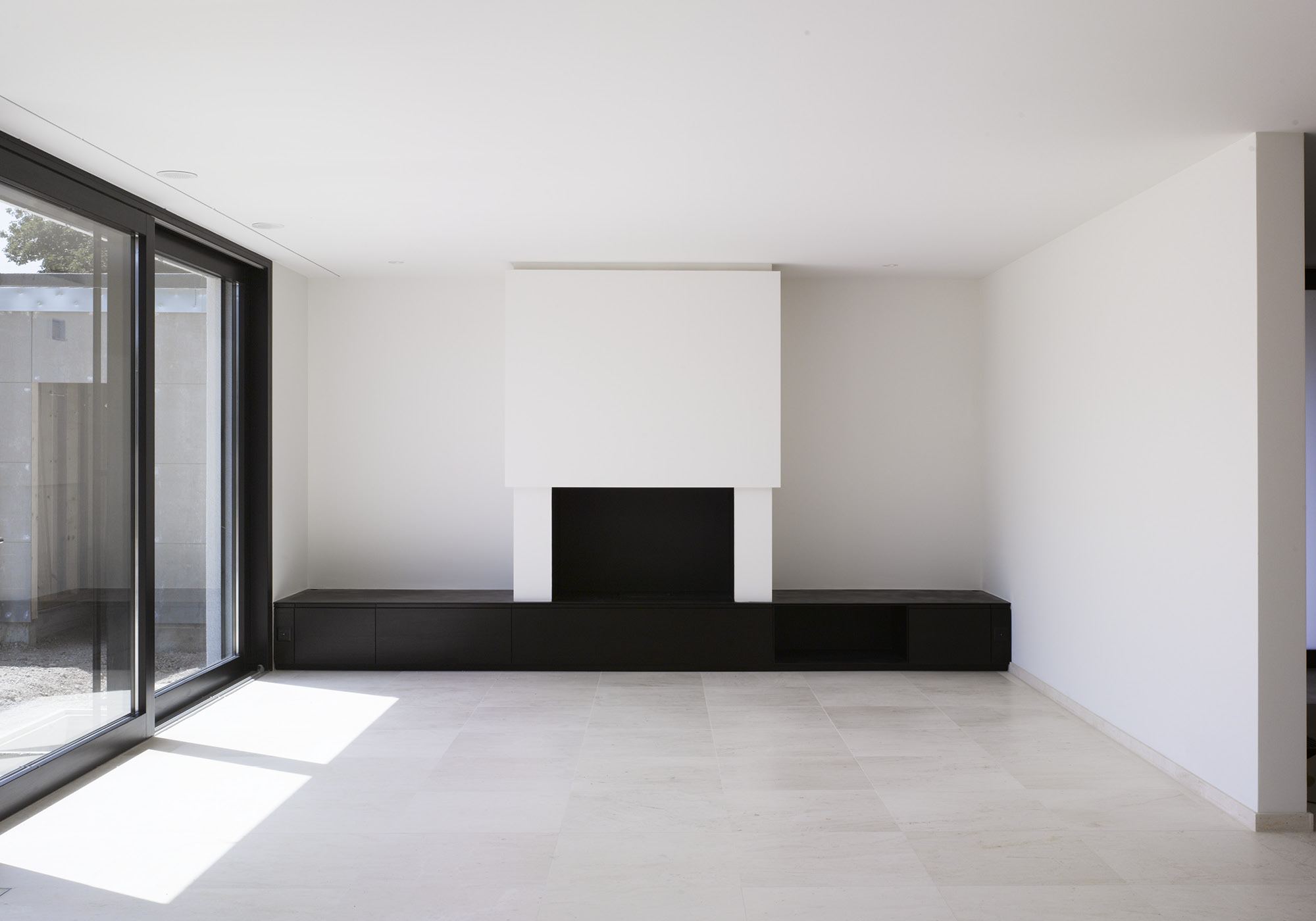 Empty living space with fireplace and glass front – Single-family house in Mülligen