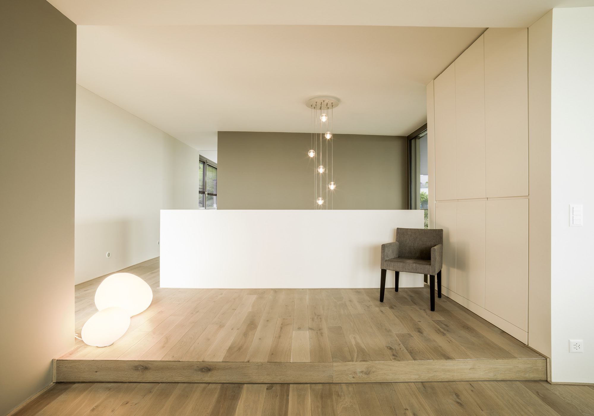 Stair landing with armchair and globe lamps – Single-family house in Schindellegi