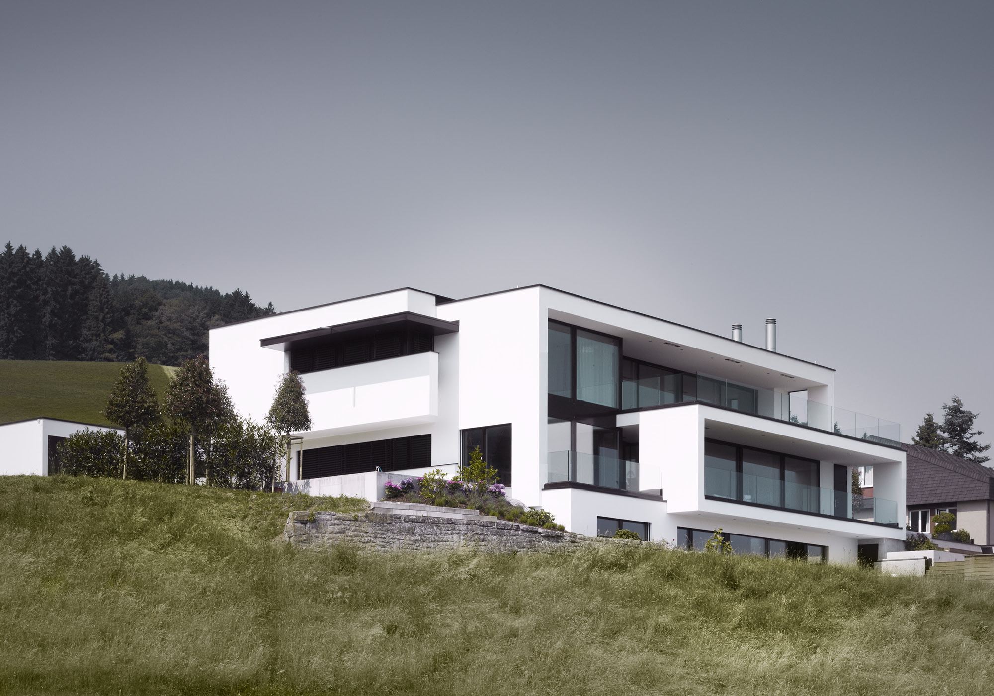 Stepped white facade on a meadow slope – Single-family house in Schindellegi