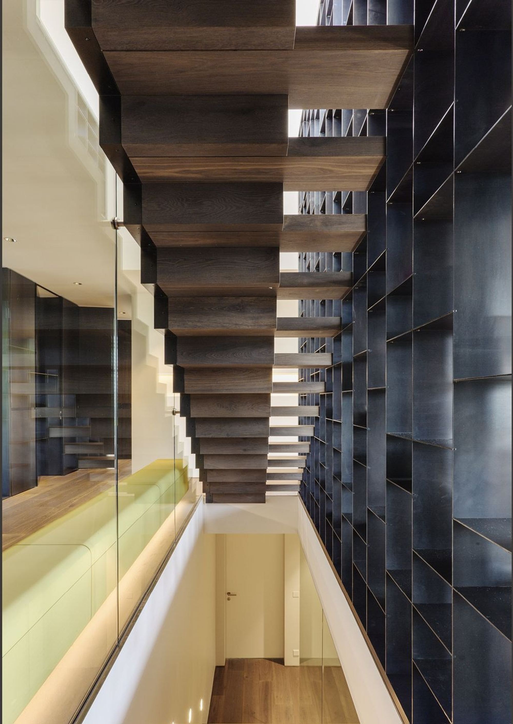 Staircase with timber treads and integrated shelving – Single-family house in Meilen