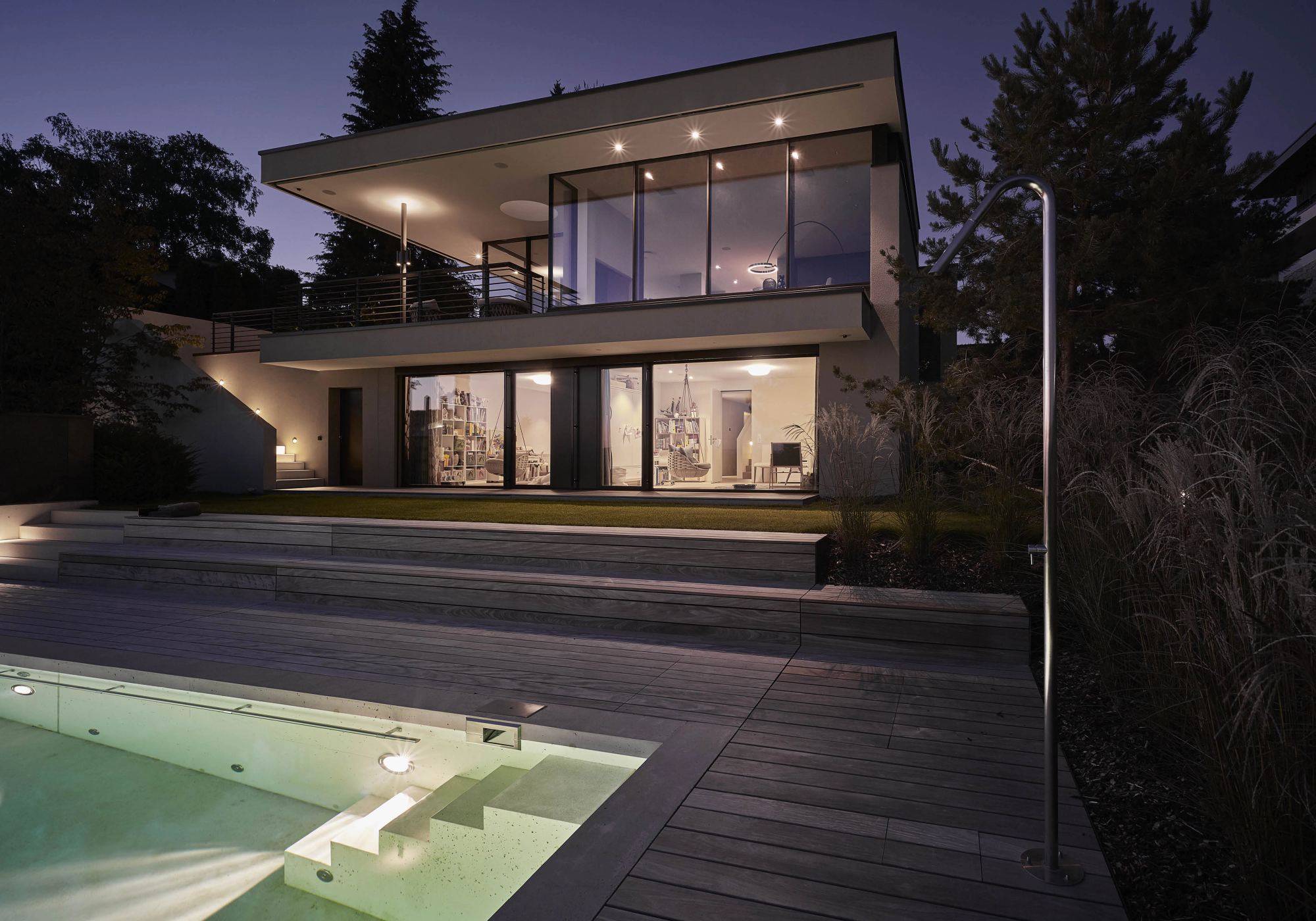 House with lit rooms and pool in the evening – Single-family house in Uitikon