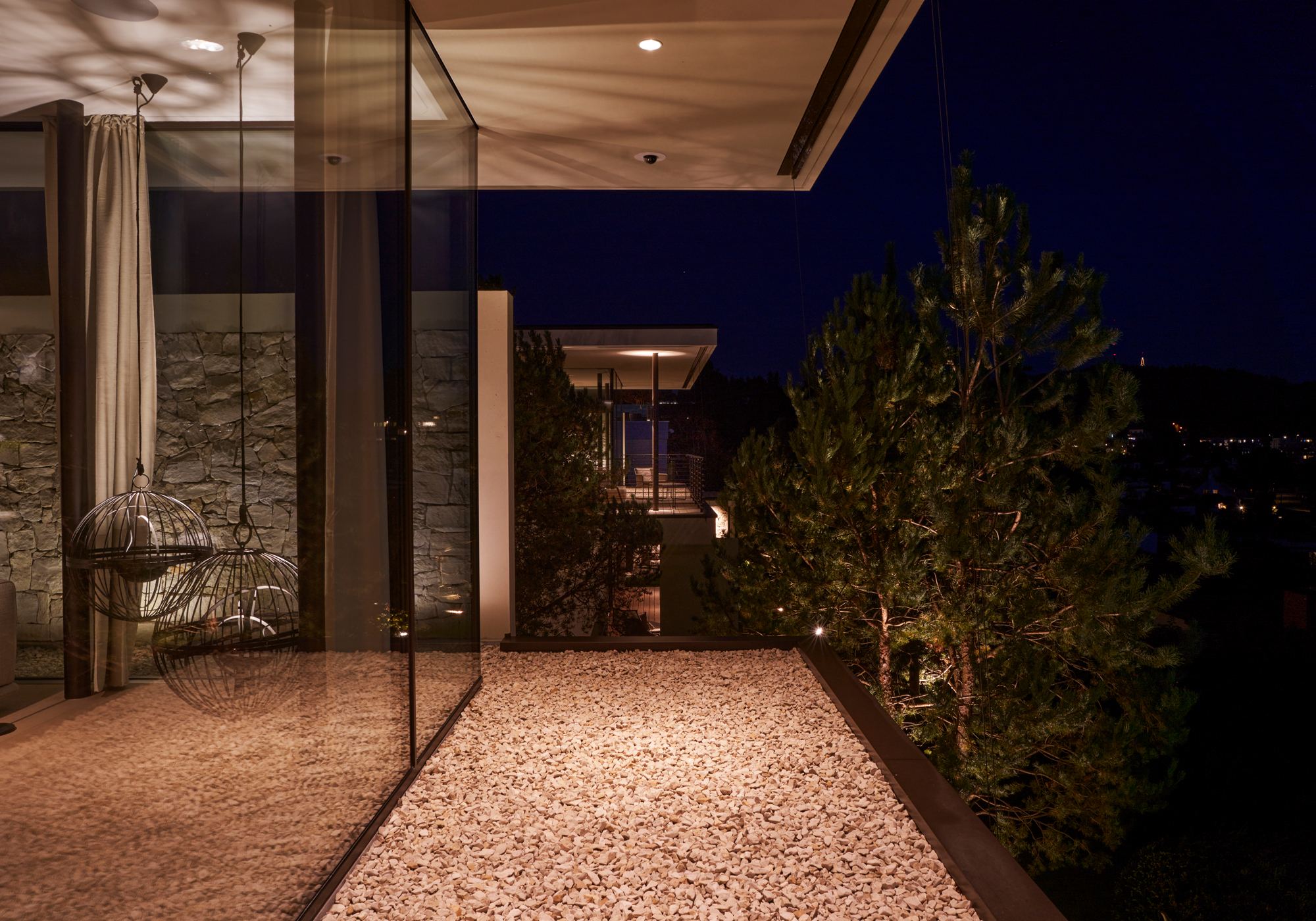 Glazed entrance with natural stone wall at night – Single-family house in Uitikon