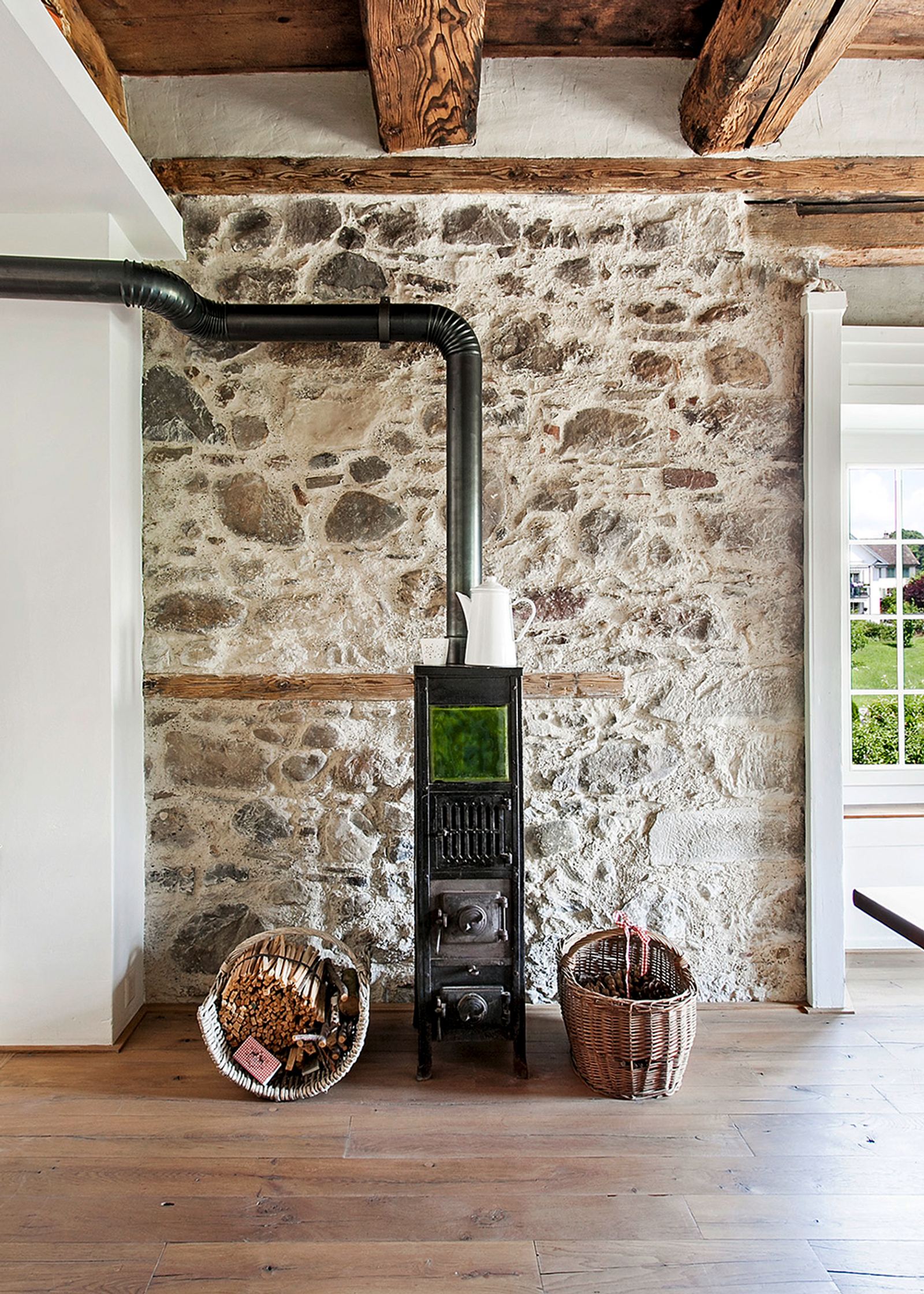 Wood stove in front of an old rubble stone wall