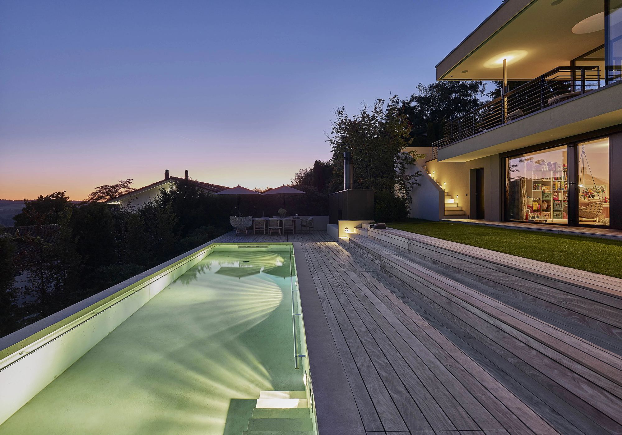 Lit pool with timber deck at dusk – Single-family house in Uitikon