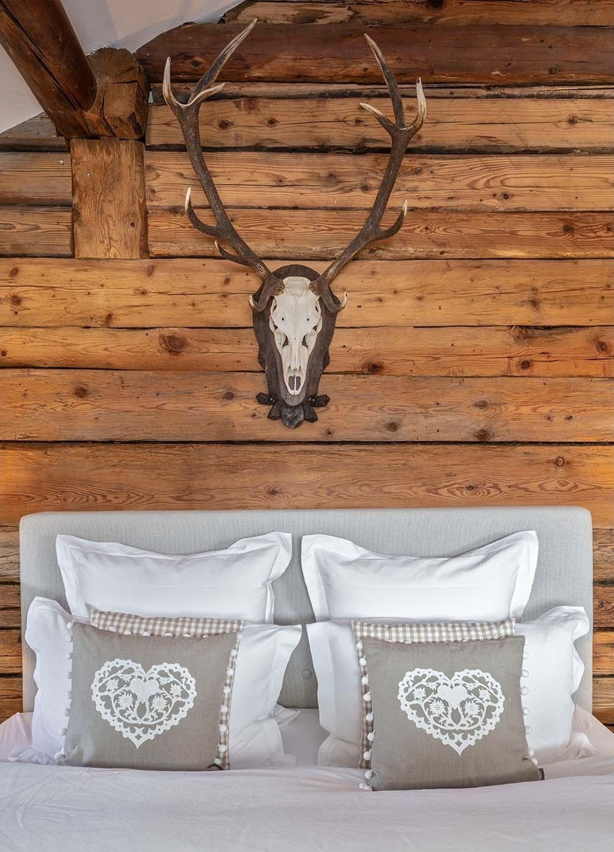 Bedhead with heart cushions below the antlers – Historic conversion in Fidaz