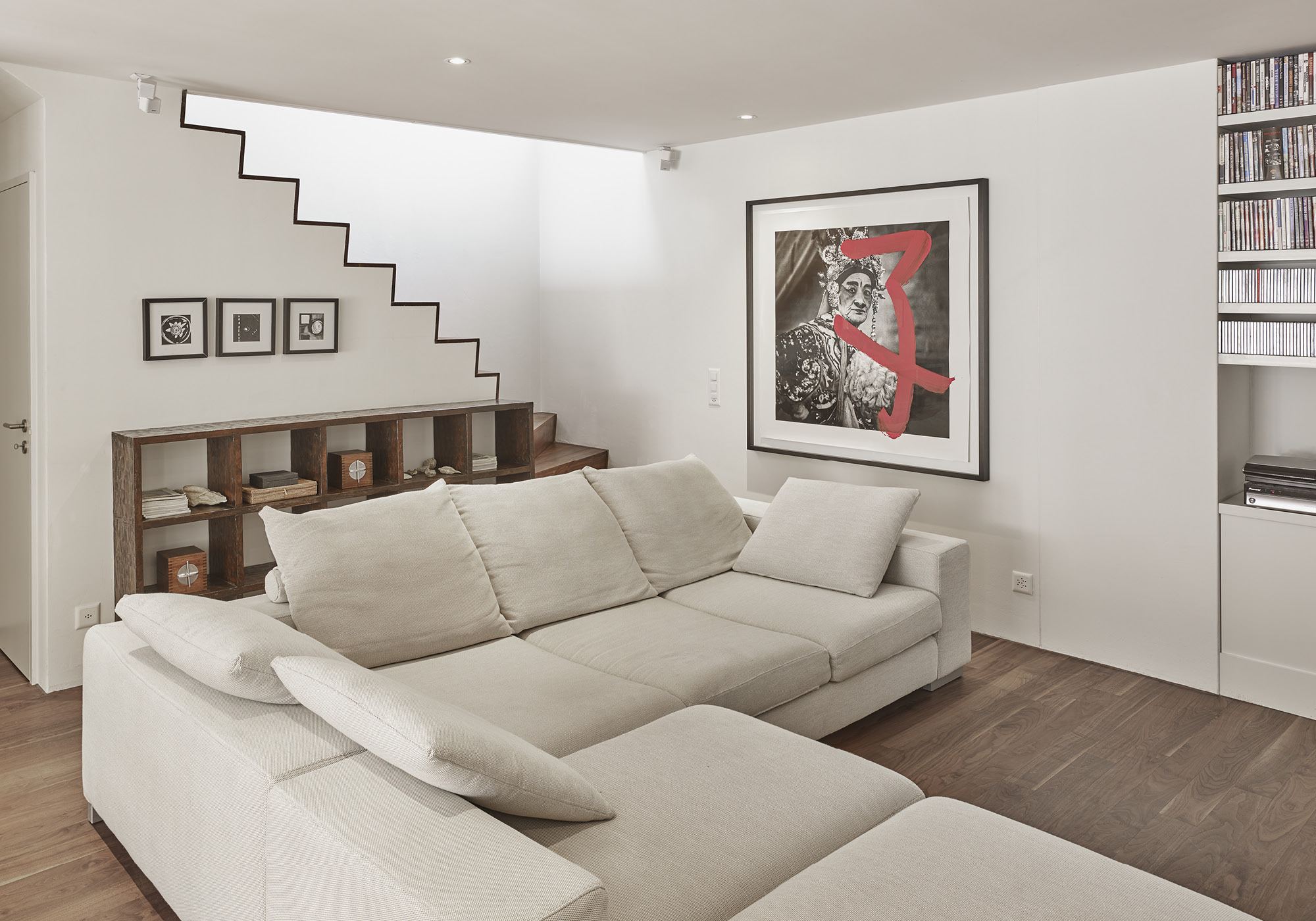 Sofa below the staircase with pictures – Apartment building in Uitikon