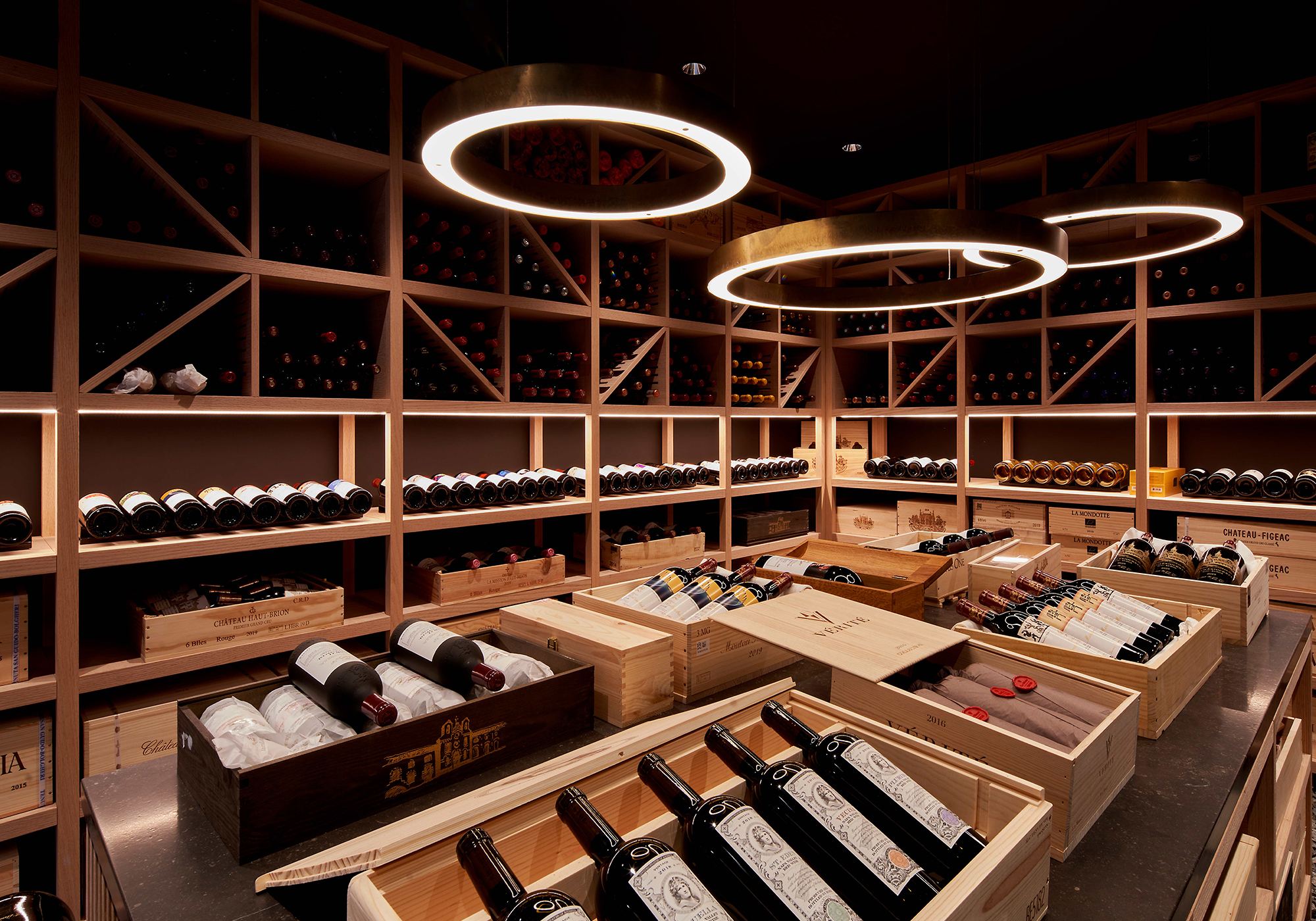 Wine cellar with timber racks, wine crates and ring lights – Single-family house in Schindellegi
