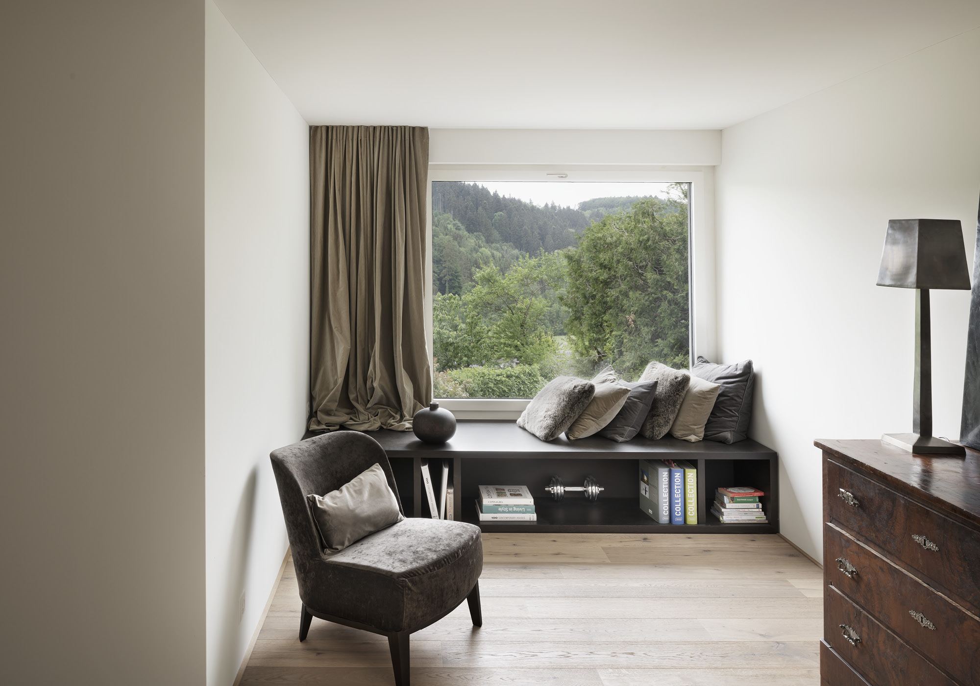 Reading corner with armchair by a window onto greenery – Interiors and landscape, Stallikon