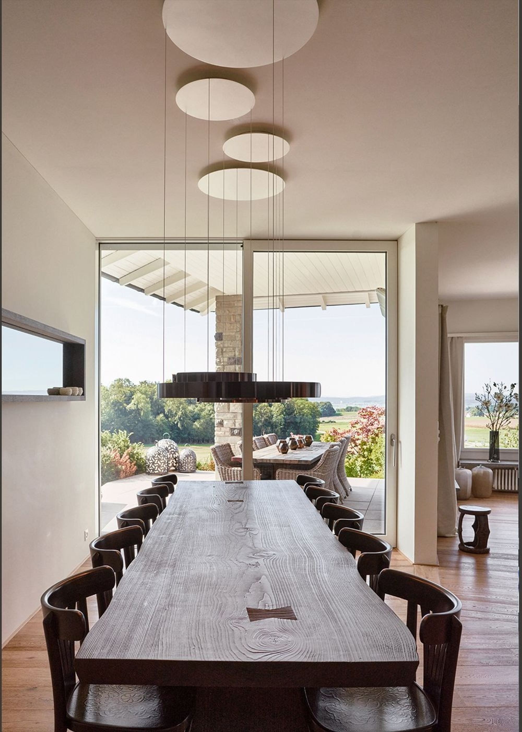 Long dining table with pendant lights and window front – Interiors and landscape, Lufingen