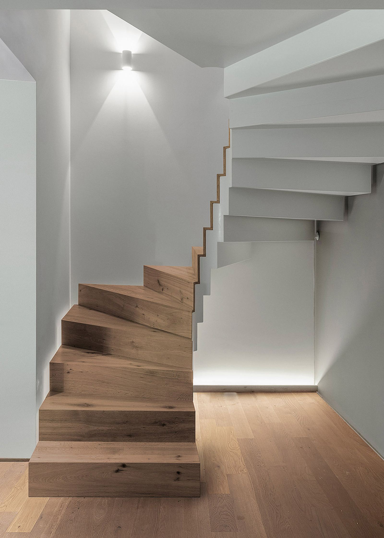 Winding timber staircase with wall light