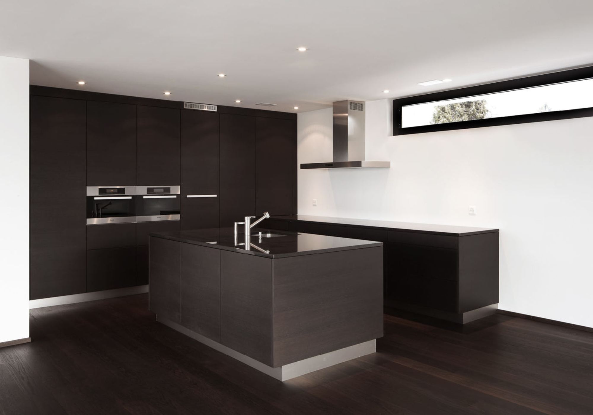 Dark kitchen run with island and ribbon window – Apartment building in Uitikon