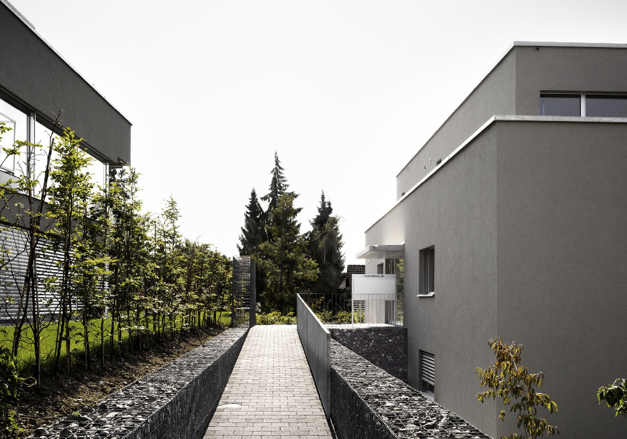 Path between gabions and trees – Apartment building in Mellingen