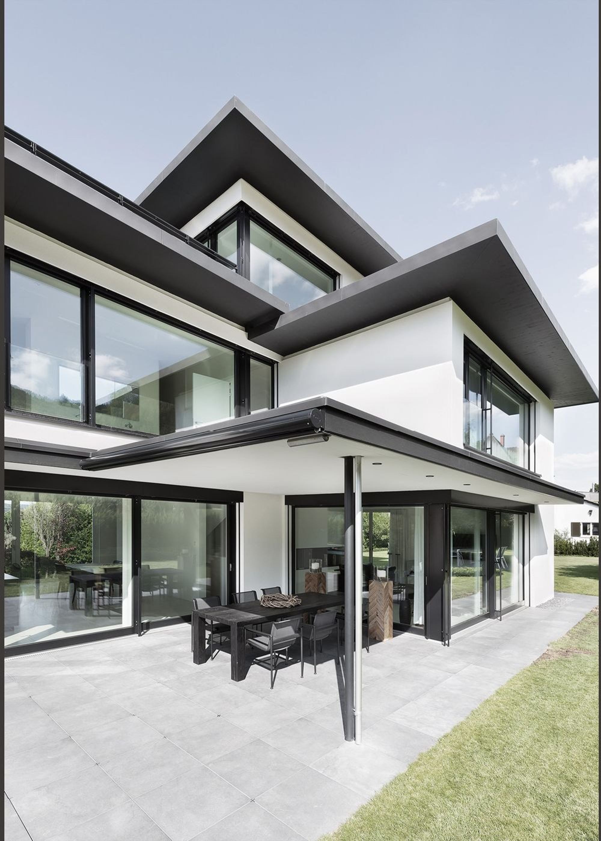 Covered seating area below wide overhanging roofs – Single-family house in Zürich