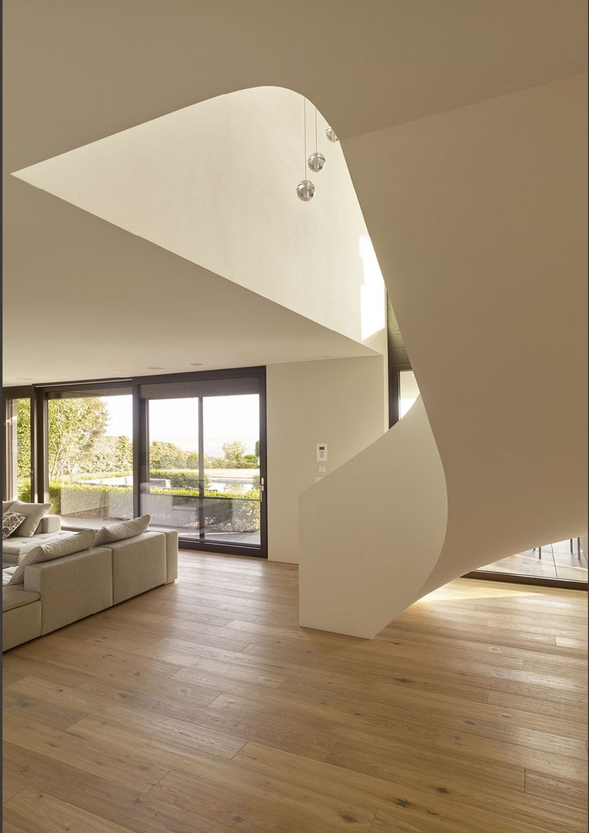 Curved white staircase in the living space – Single-family house in Oberwil-Lieli