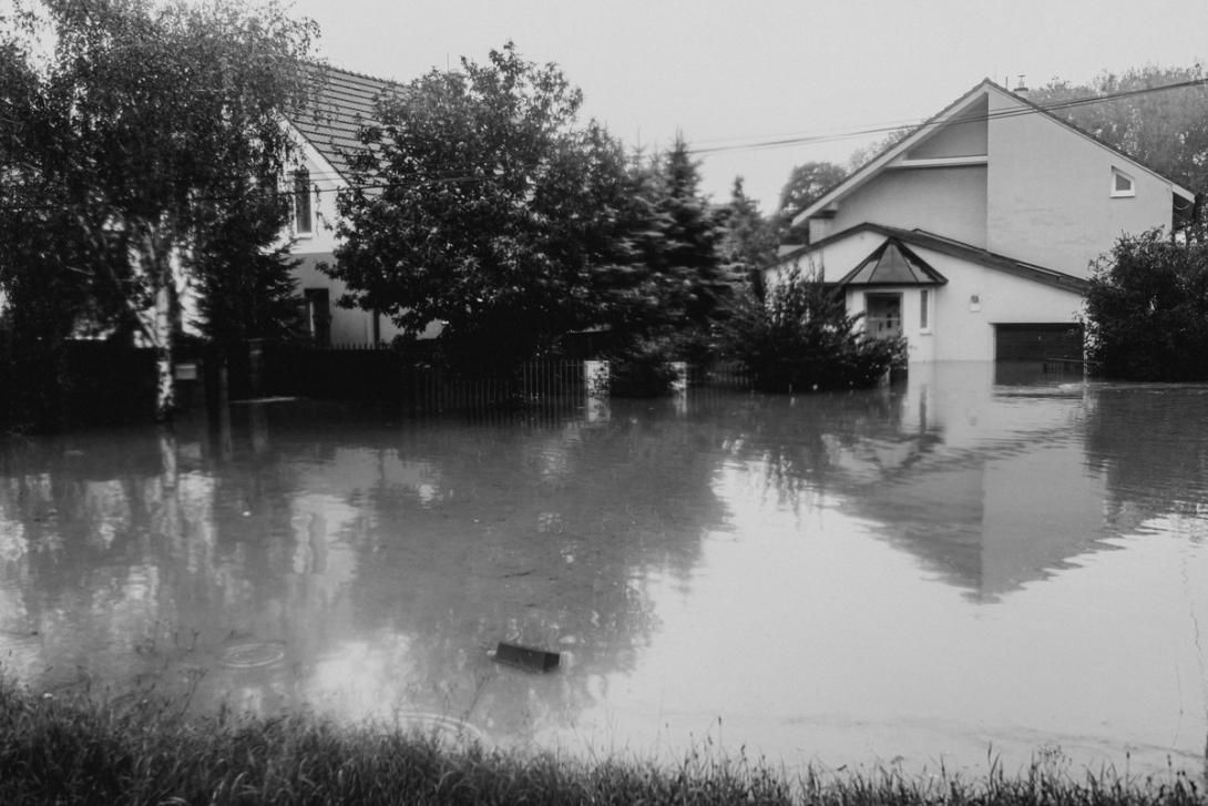 Black and white photo of a flooded street with houses partially submerged in water.