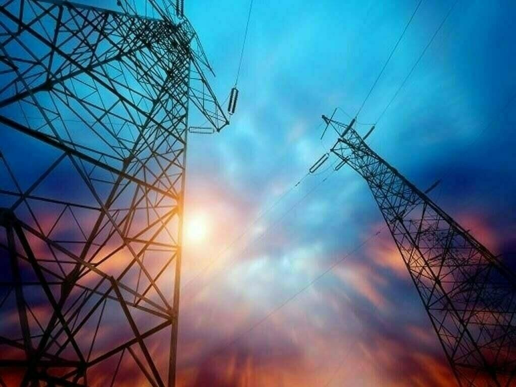 Two power transmission towers silhouetted against a vibrant blue and orange sky with a sunburst.