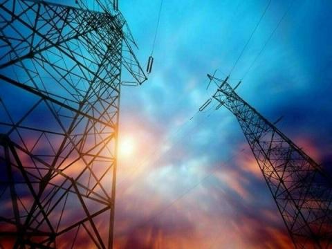 Two electricity pylons silhouetted against a dramatic, colorful sky with a bright sun.