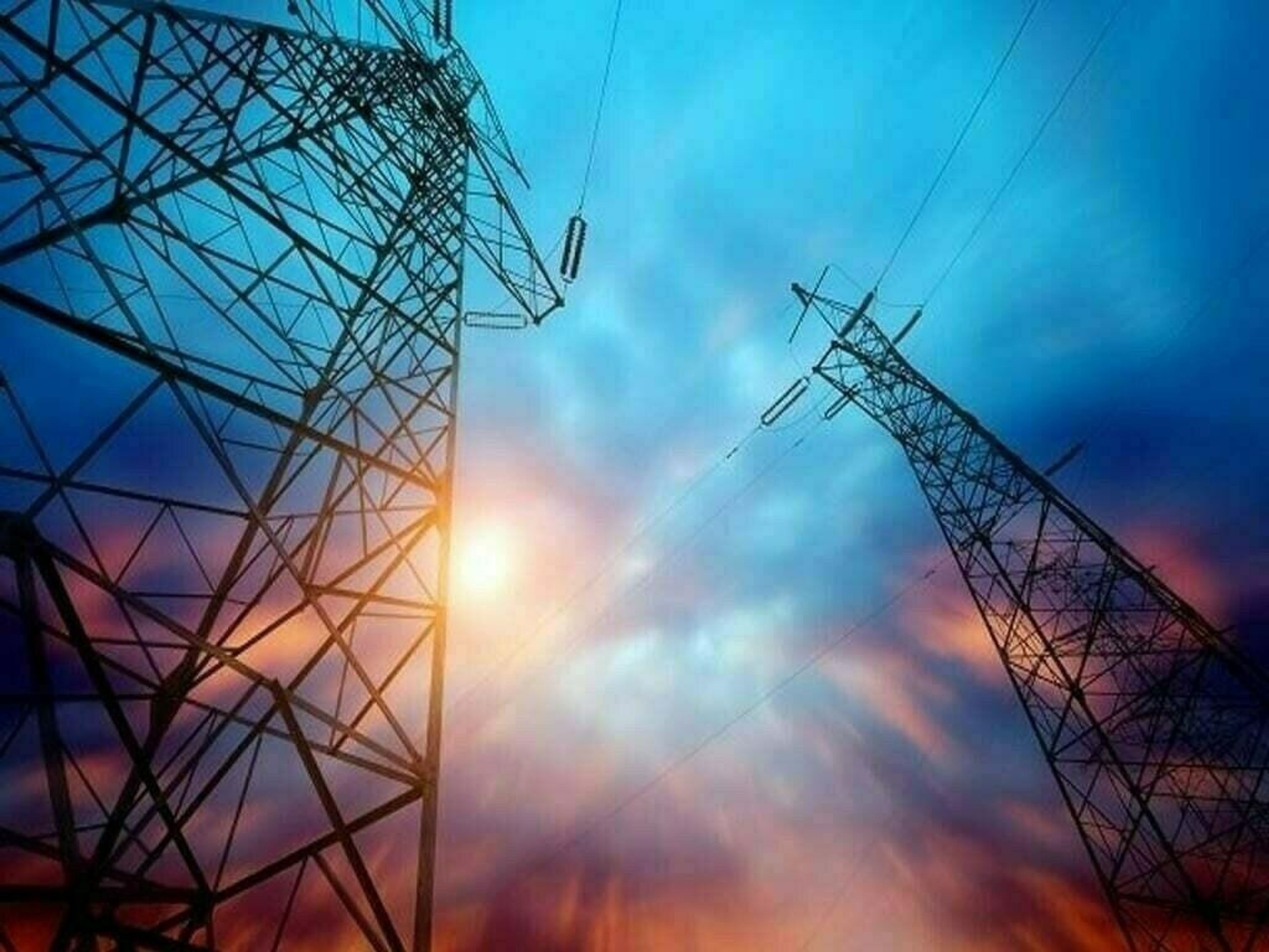 Two power transmission towers silhouetted against a vibrant blue and orange sky with a sunburst.