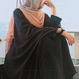 A person in a black abaya and peach hijab with blue accents, sitting thoughtfully with white sneakers, overlaid with a retro VHS filter.
