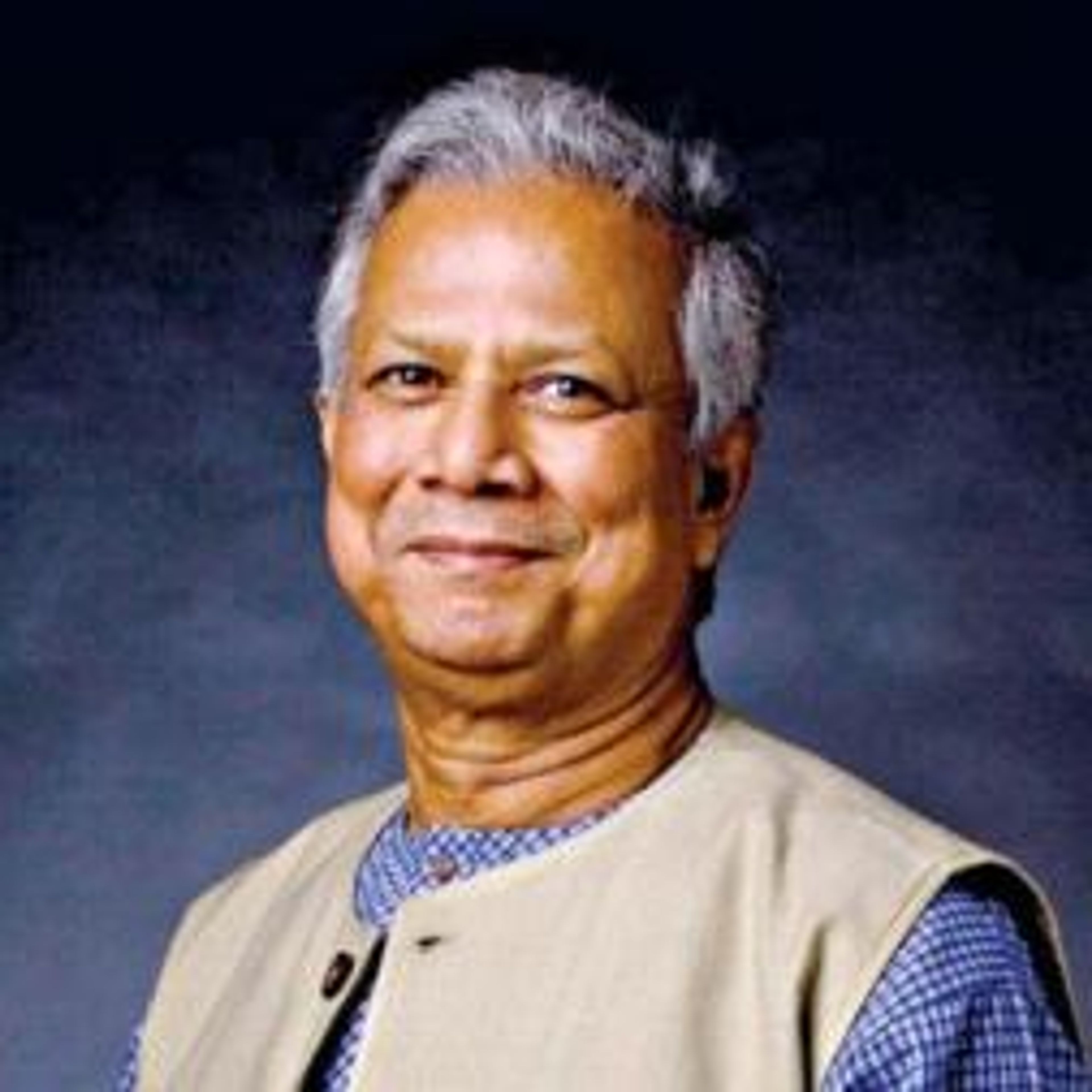 Smiling man with gray hair in a blue shirt and light brown vest.