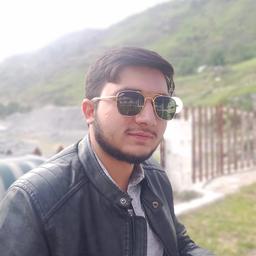 Young man in gold aviator sunglasses and a black leather jacket, with blurry green hills in the background.