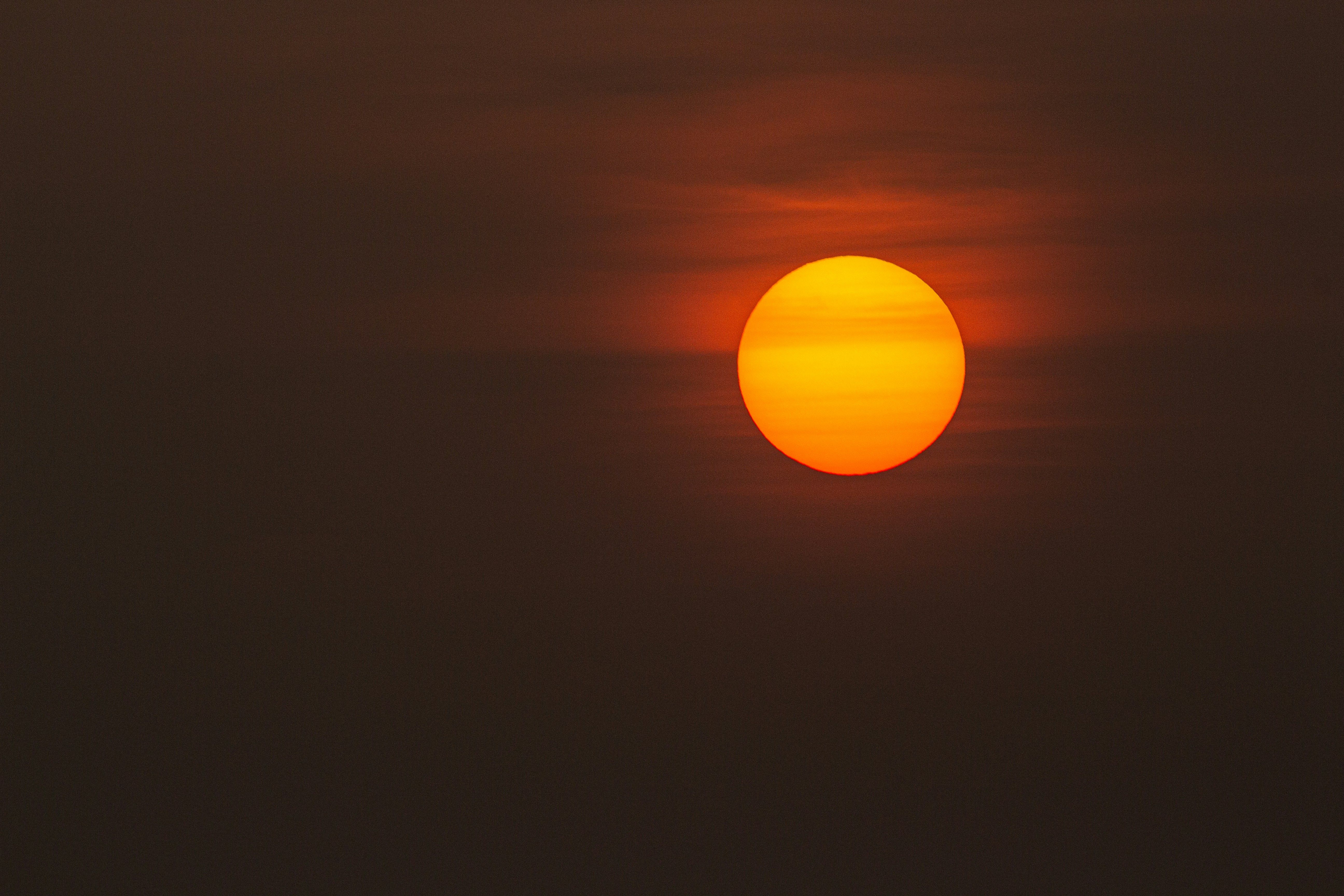 Bright orange sun in a hazy, dark sky.