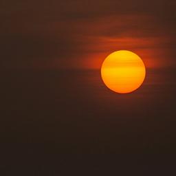 Bright orange sun in a hazy, dark sky.