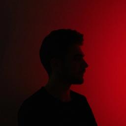 Man's silhouette in profile against a red gradient background.