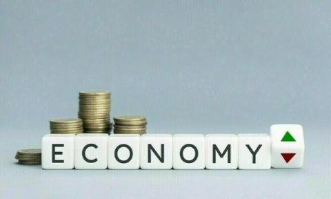 The word "ECONOMY" spelled with letter blocks, stacks of coins, and a block showing up and down arrows.