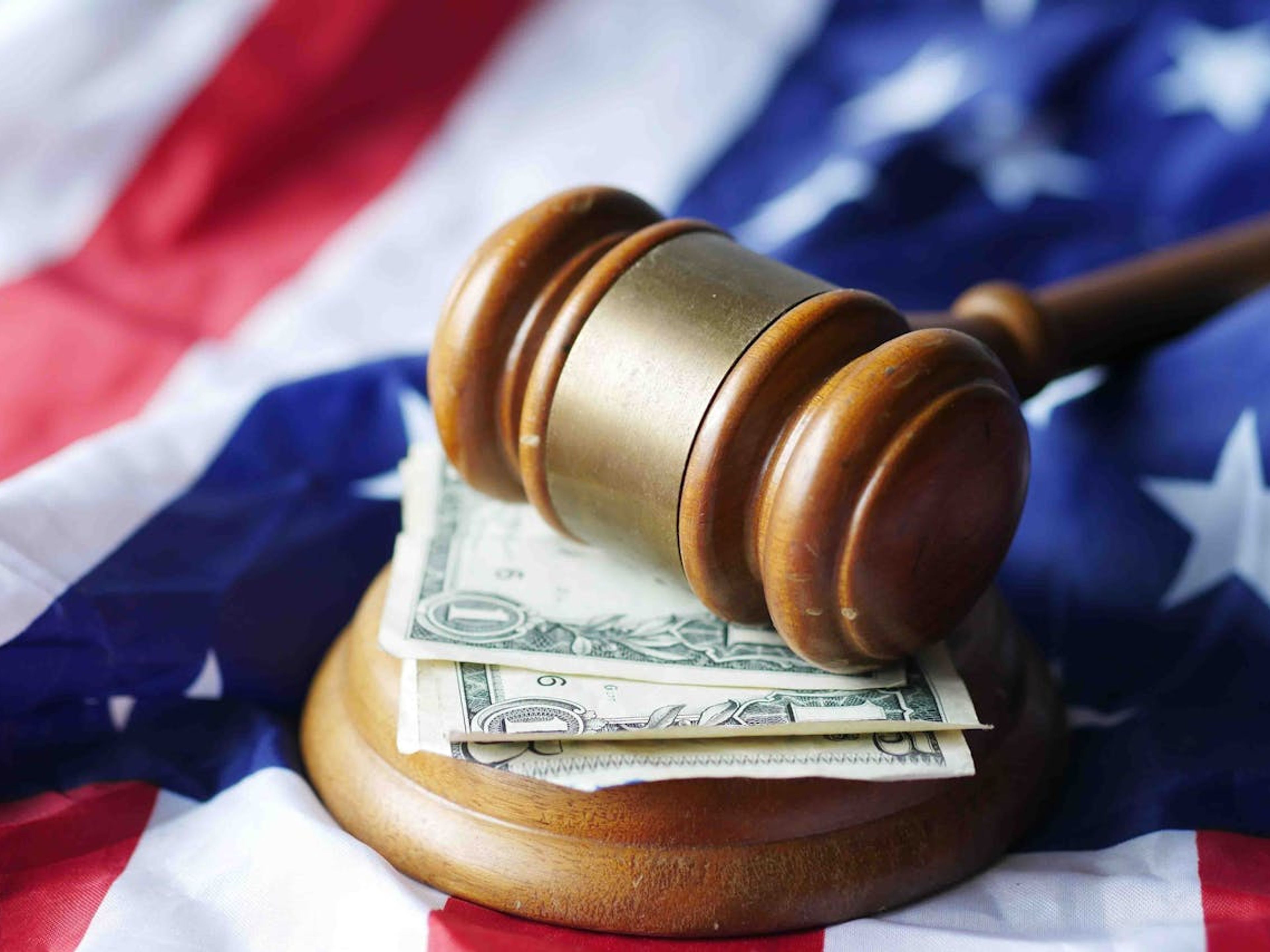 A person with a book leans on a stone railing, overlooking historic buildings.