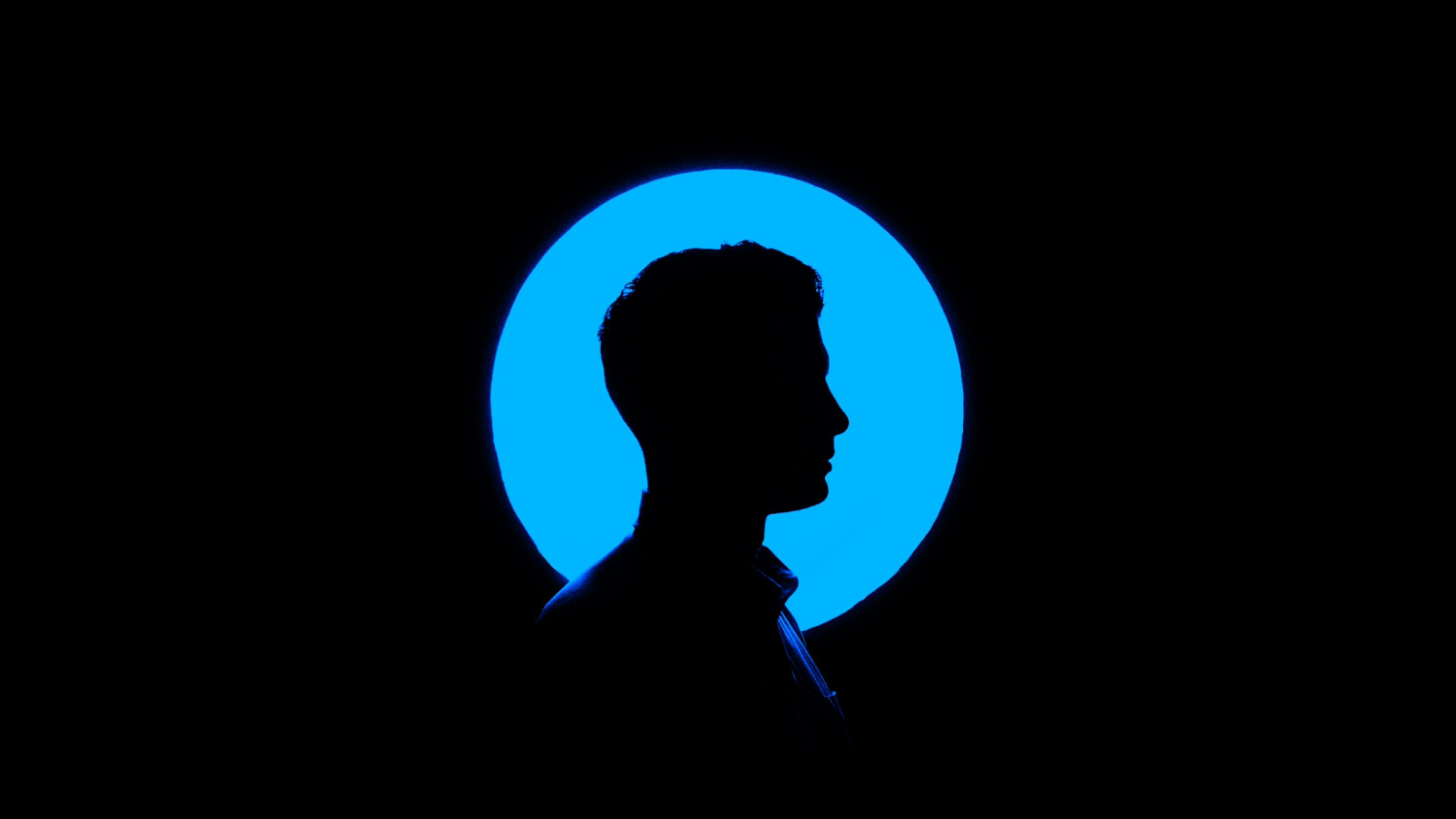 Man's silhouette in profile against a glowing blue circle.