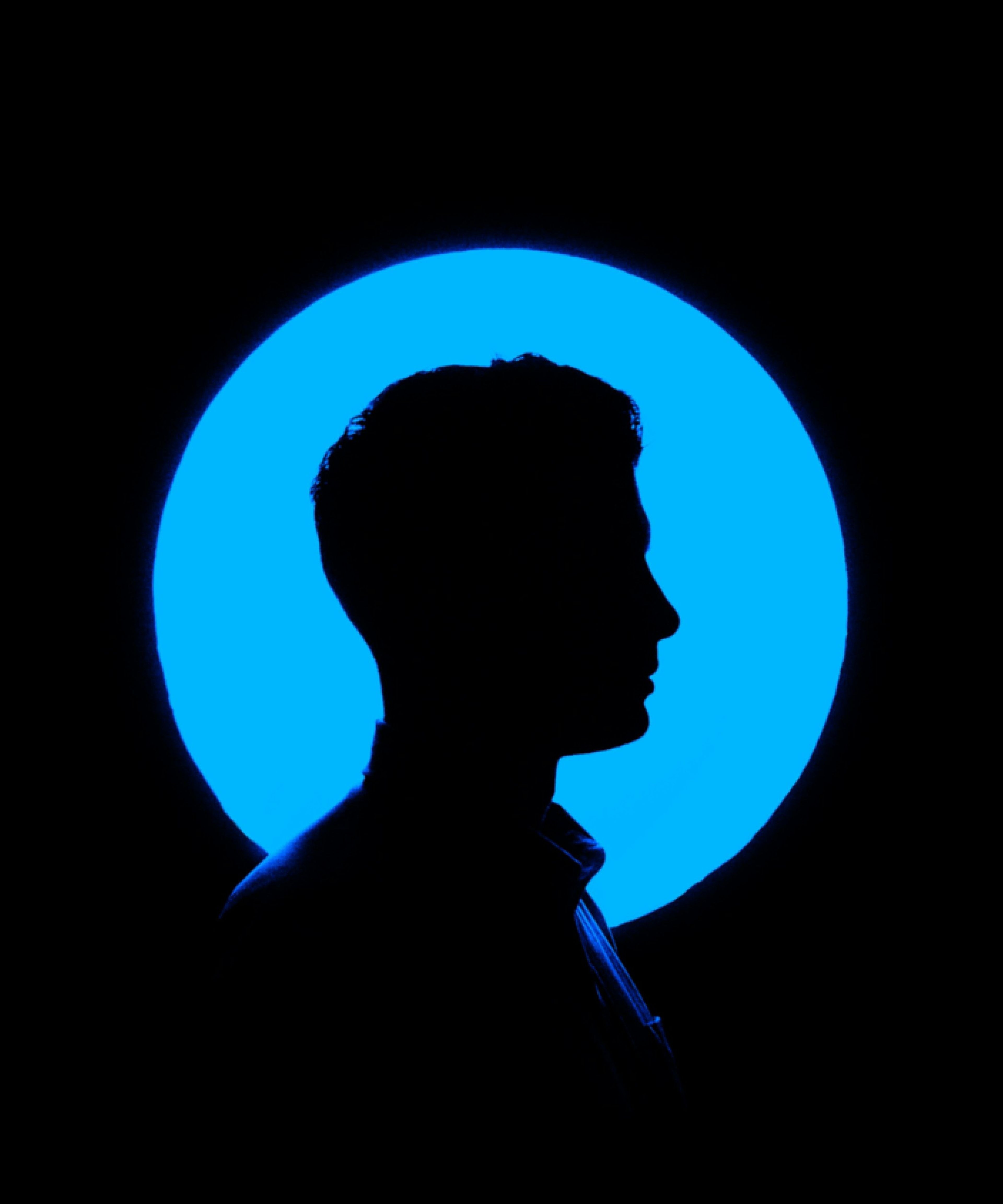Man's profile silhouette against a glowing blue circle on a black background.