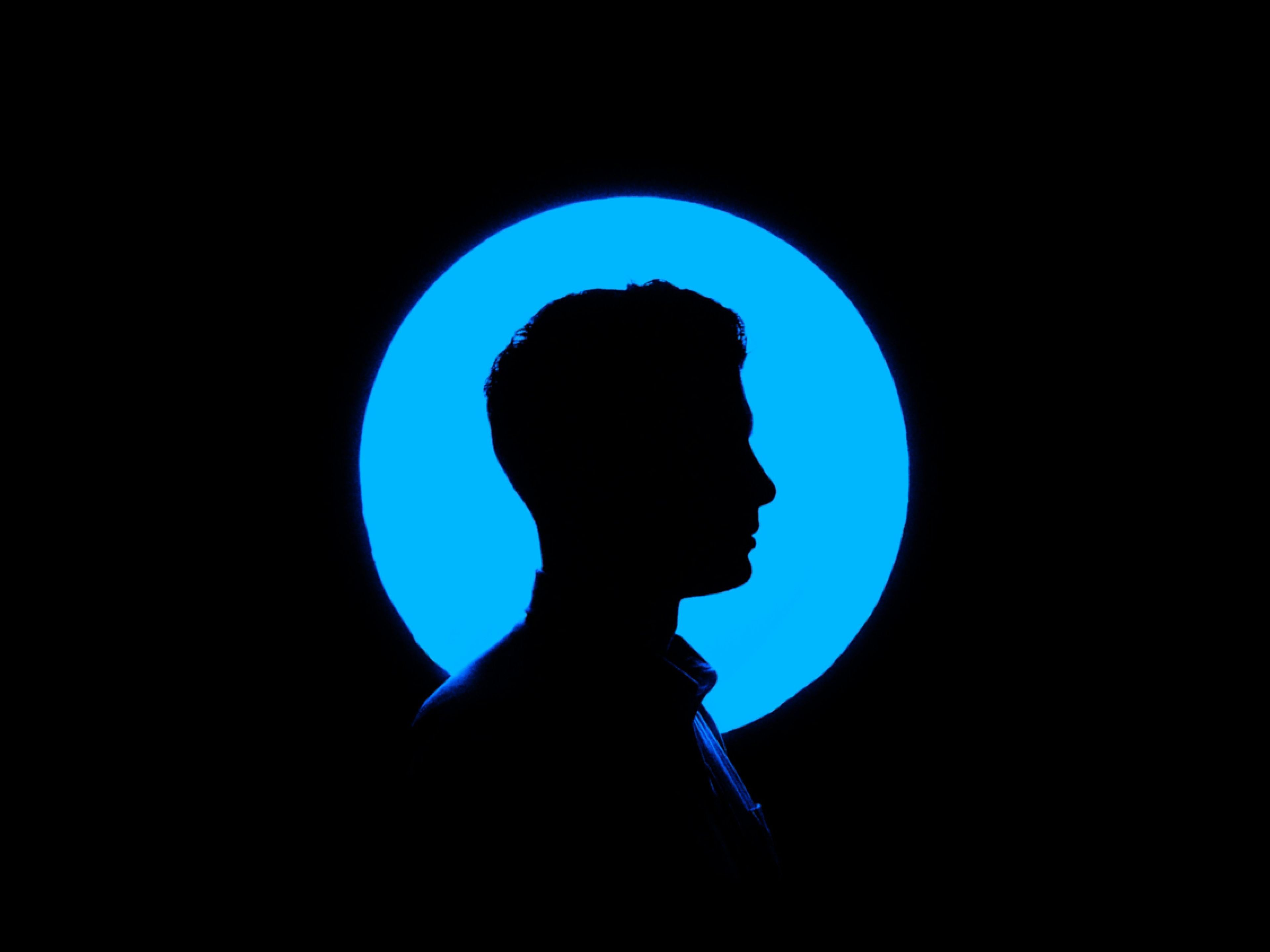 Man's silhouette in profile against a glowing blue circle.